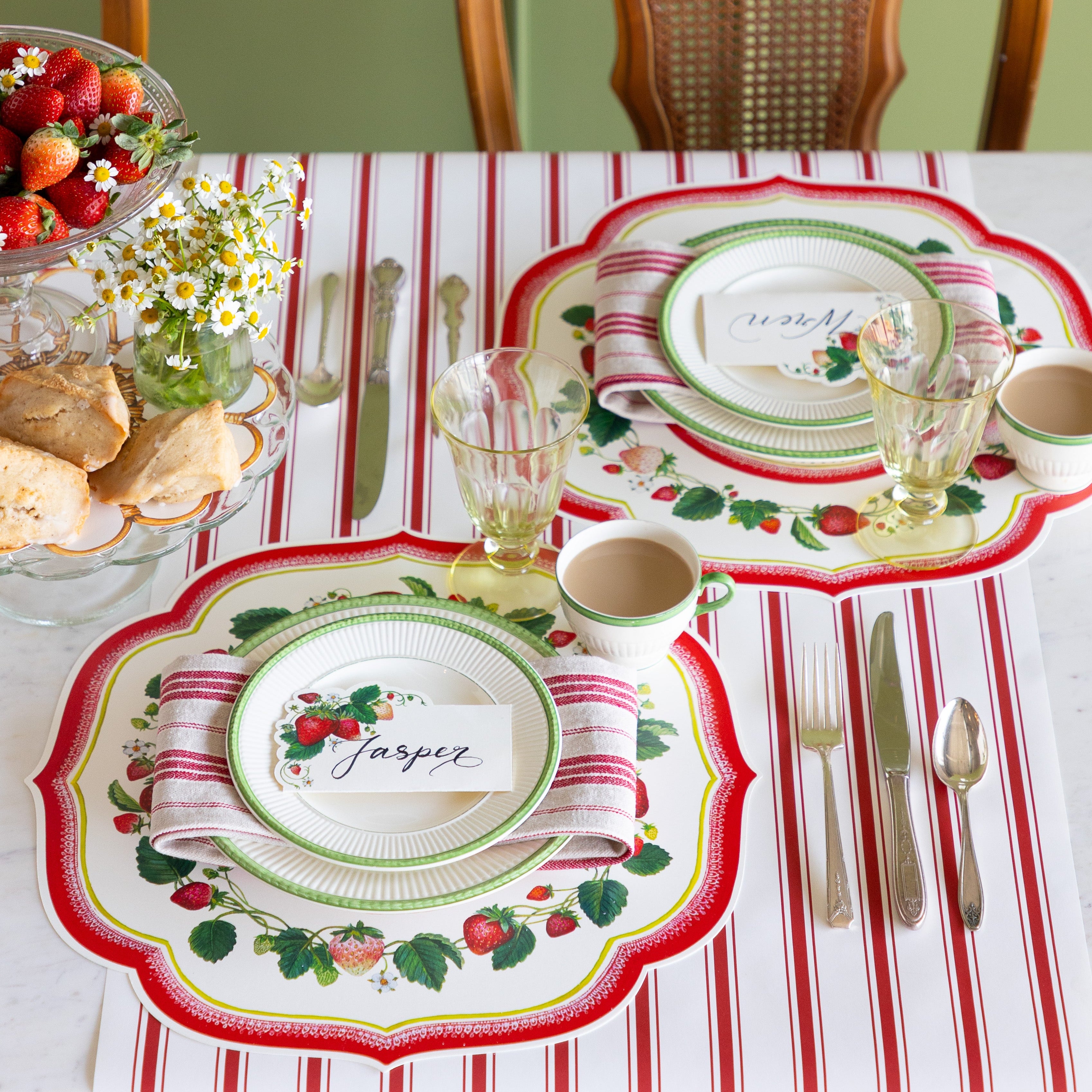 Decorative table setting with treats, Die-cut Strawberry China Placemats, Strawberry Place Card, red striped napkins and vintage cutlery on the Red Linen Stripe Runner.
