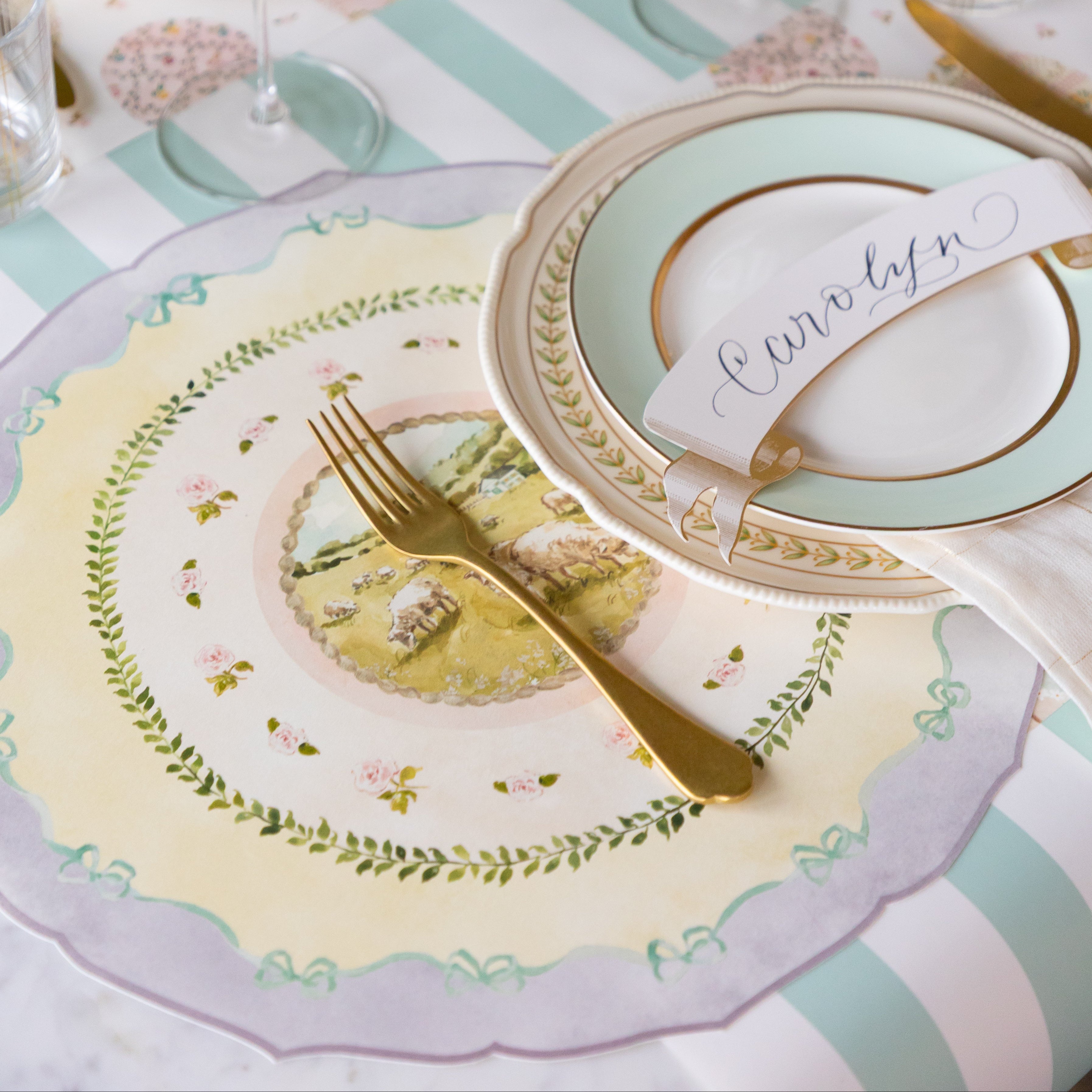 Elegant place setting with the Die-cut Spring Meadow Placemat, decorative plates, Classic Gold Banner Table Accent and gold cutlery on the Seafoam Classic Stripe Runner.