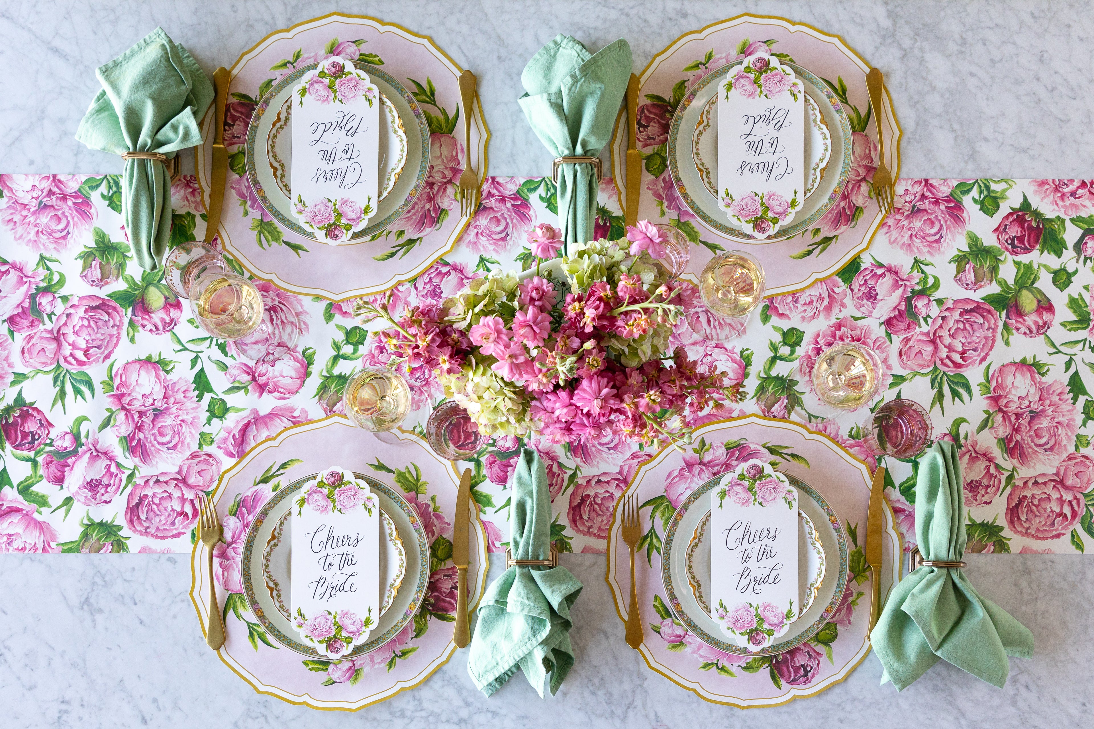 Decorative table setting with Die-cut Peony China Placemats, green rimmed and pink floral plates, vintage cutlery and flowers on the Peonies in Bloom Runner.