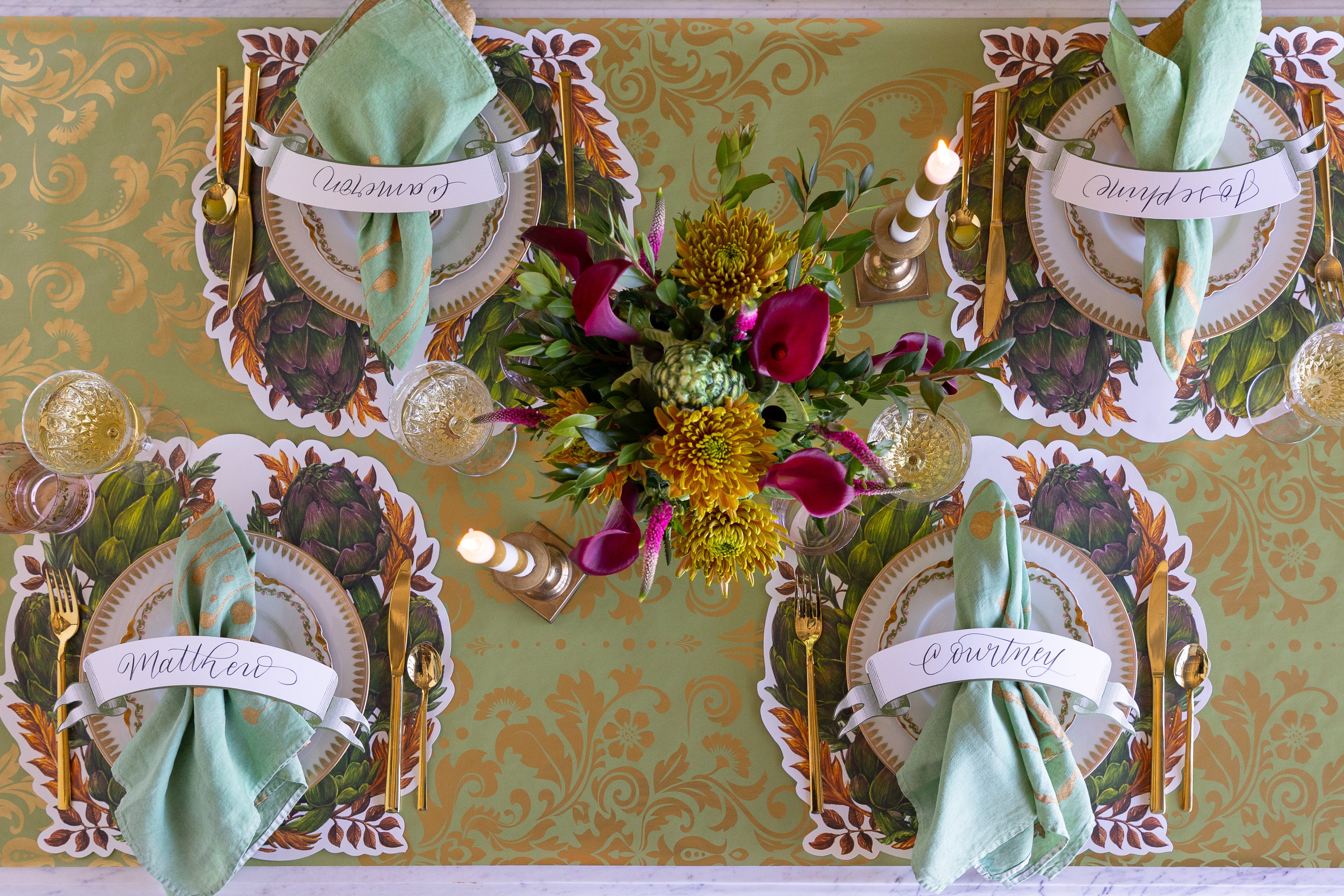 Decorative table setting with place cards, napkins, and a floral centerpiece on a patterned tablecloth.