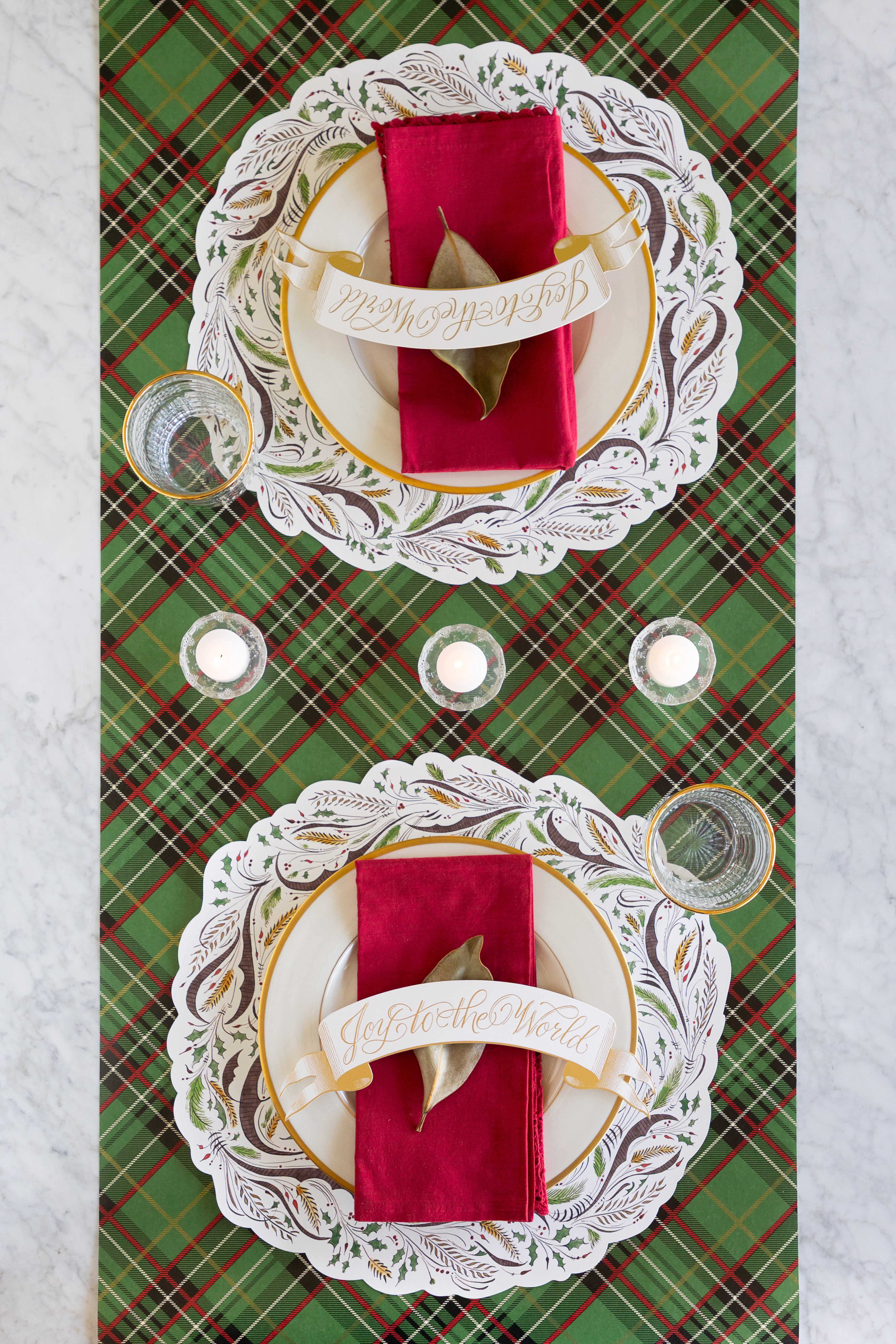 Decorative table setting with red napkins and ornate place cards on a plaid table runner.