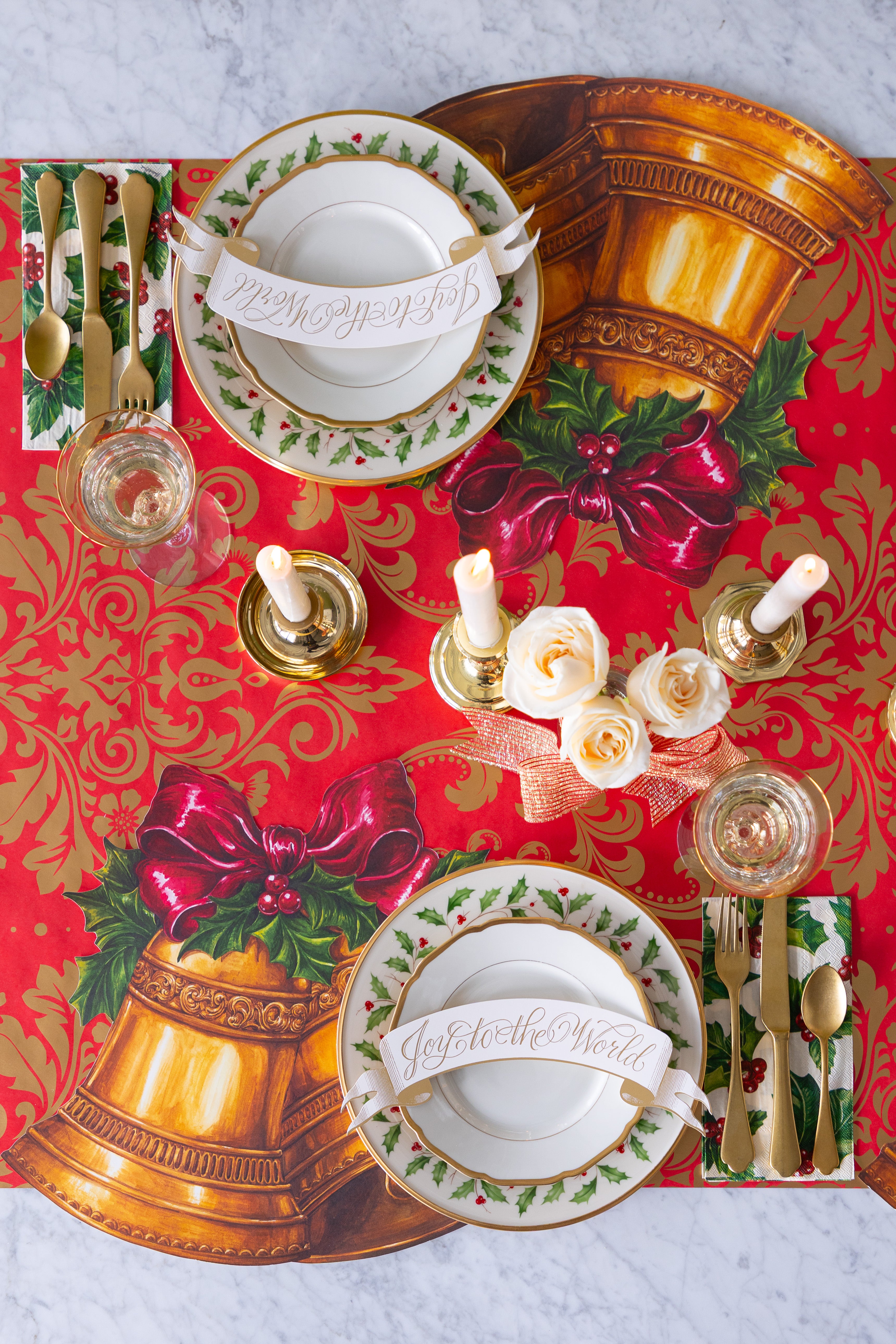 Elegant Holiday table setting with the Die-cut Christmas Bells Placemat with plates, flowers and cutlery.