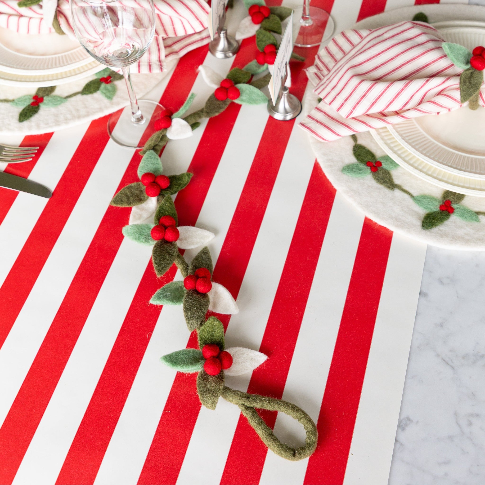 A festive table setting featuring the Felt Berry Garland going down the center of the table in a wavy motion.
