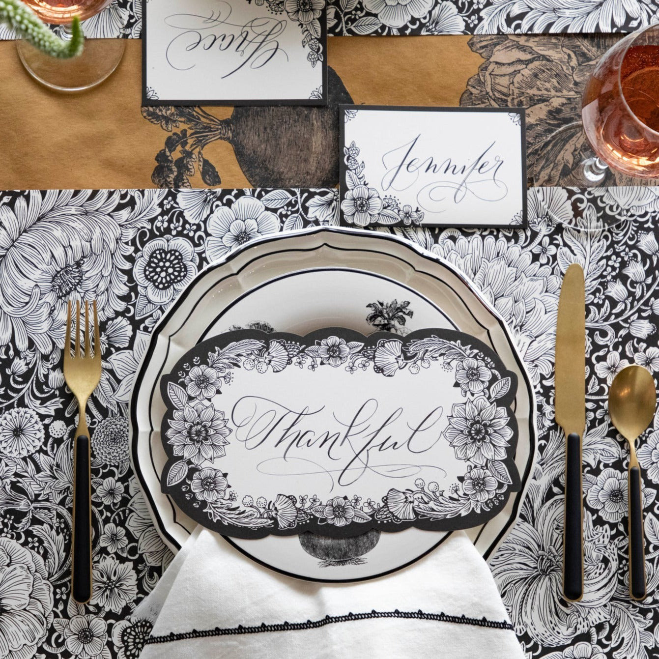 An elegant place setting featuring an Ebony Harvest Blooms Table Card with "Thankful" written on it in lovely script resting on the plate.