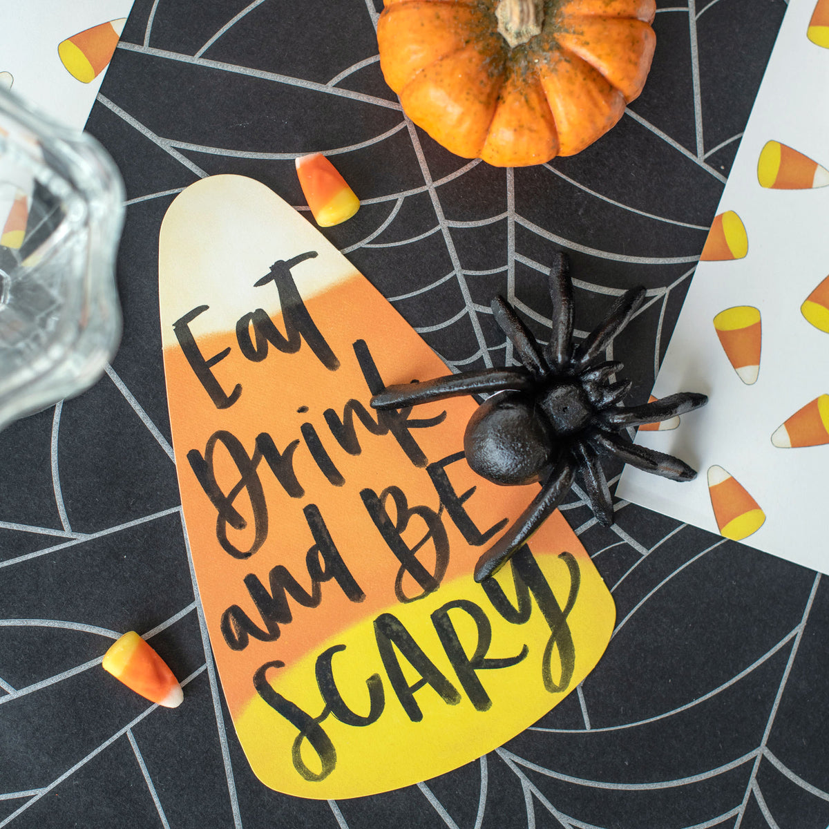 Close-up of a Candy Corn Table Accent resting on a spooky table setting, with "Eat Drink and Be Scary" written on it.