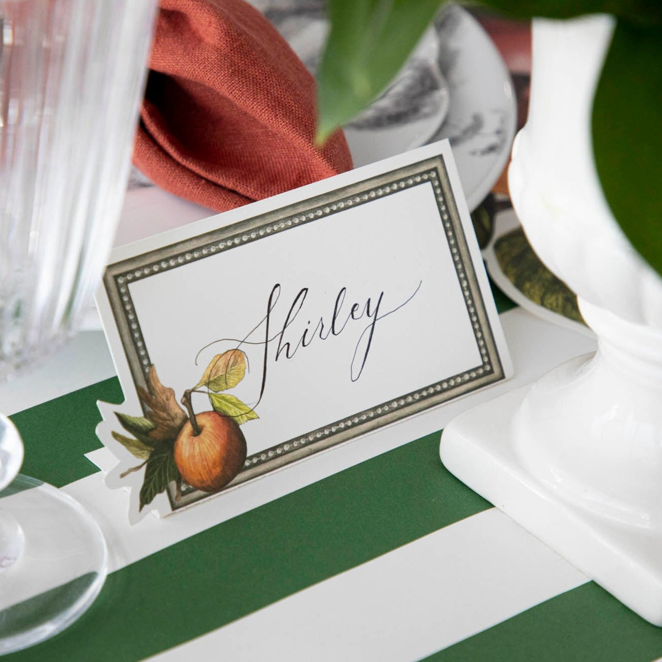 Close-up of a Heirloom Apples Place Card labeled &quot;Shirley&quot; as part of an elegant table setting.