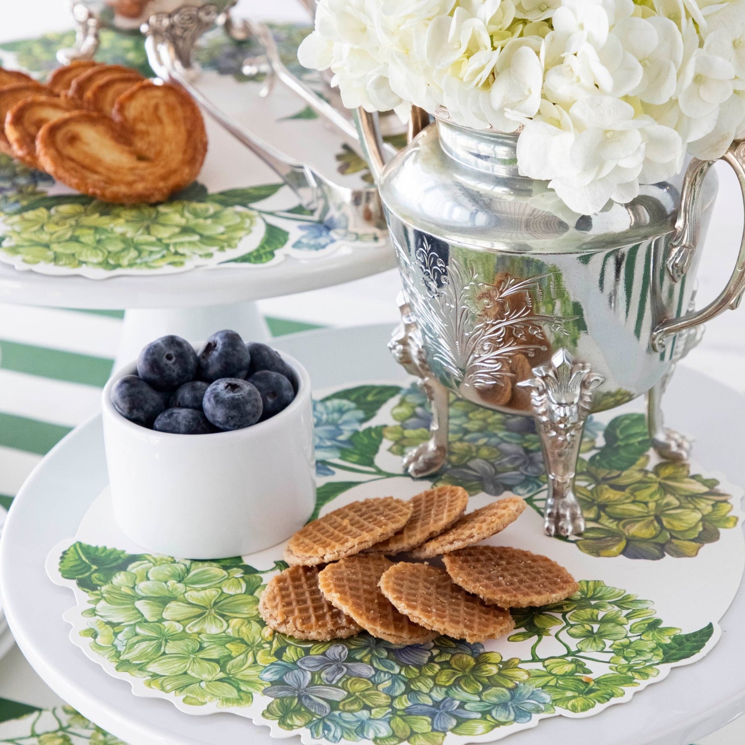 Close-up of the Hydrangea Serving Papers featured in an elegant treat spread with cake stands and vases of flowers.