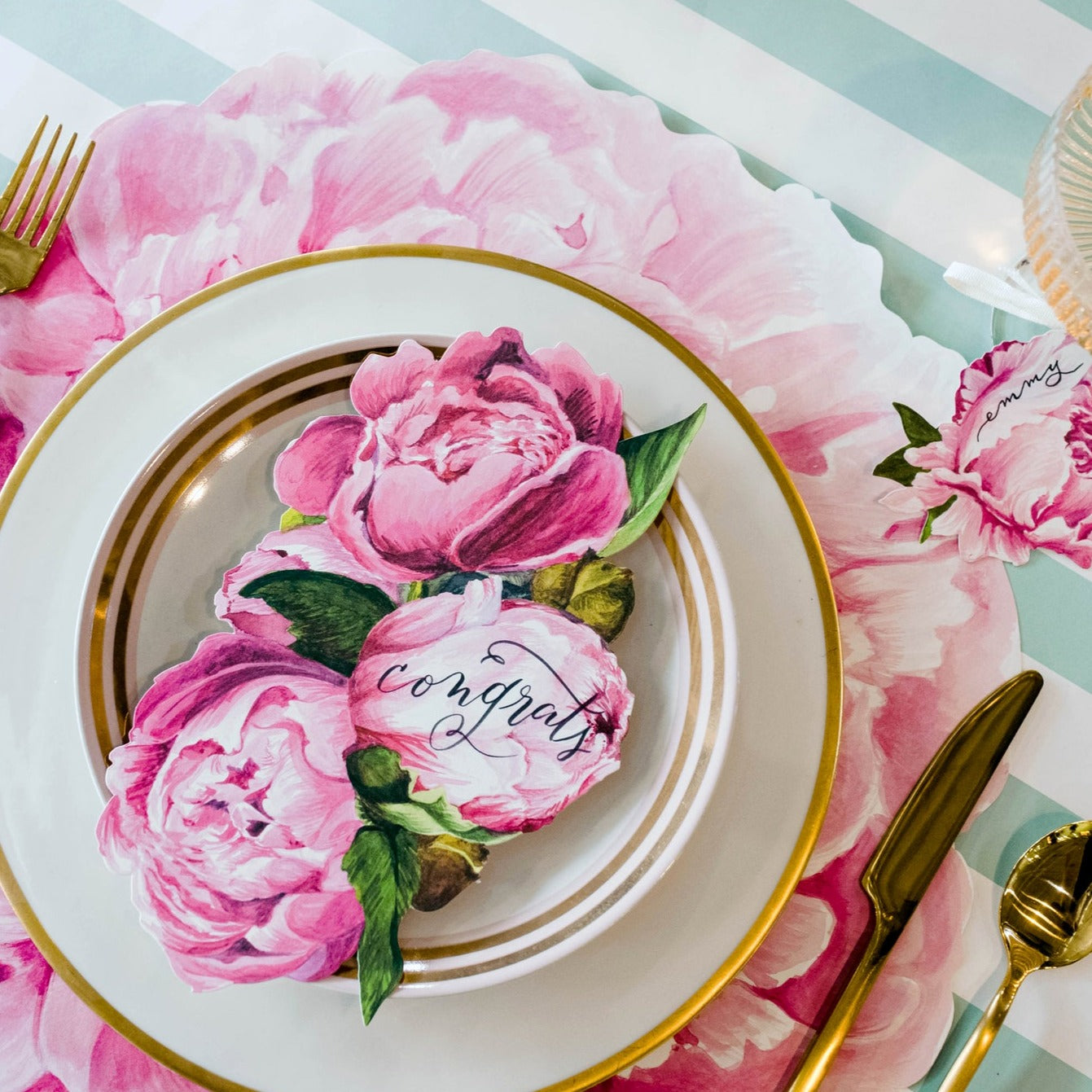 An elegant place setting featuring a Peony Table Accent with "congrats" written on it resting on the plate.
