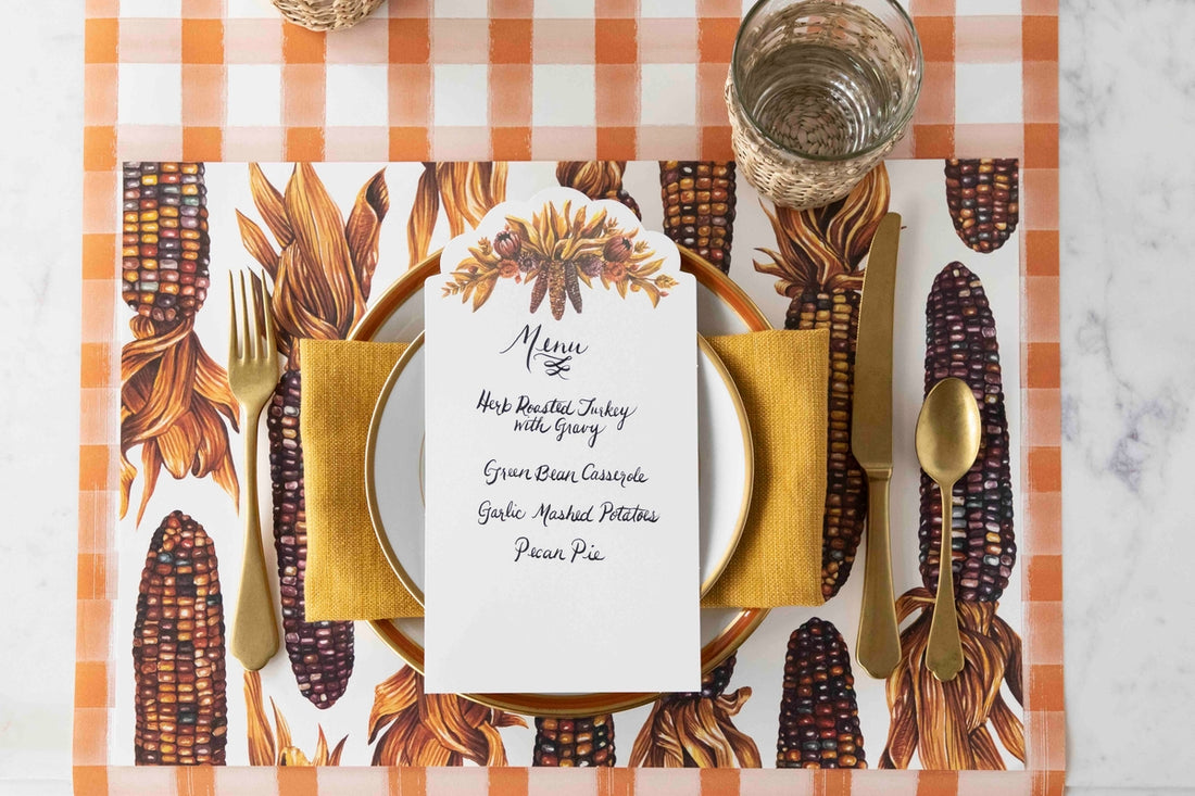 A Gathering Table Card with a menu written on it resting on the plate of an elegant Fall place setting.