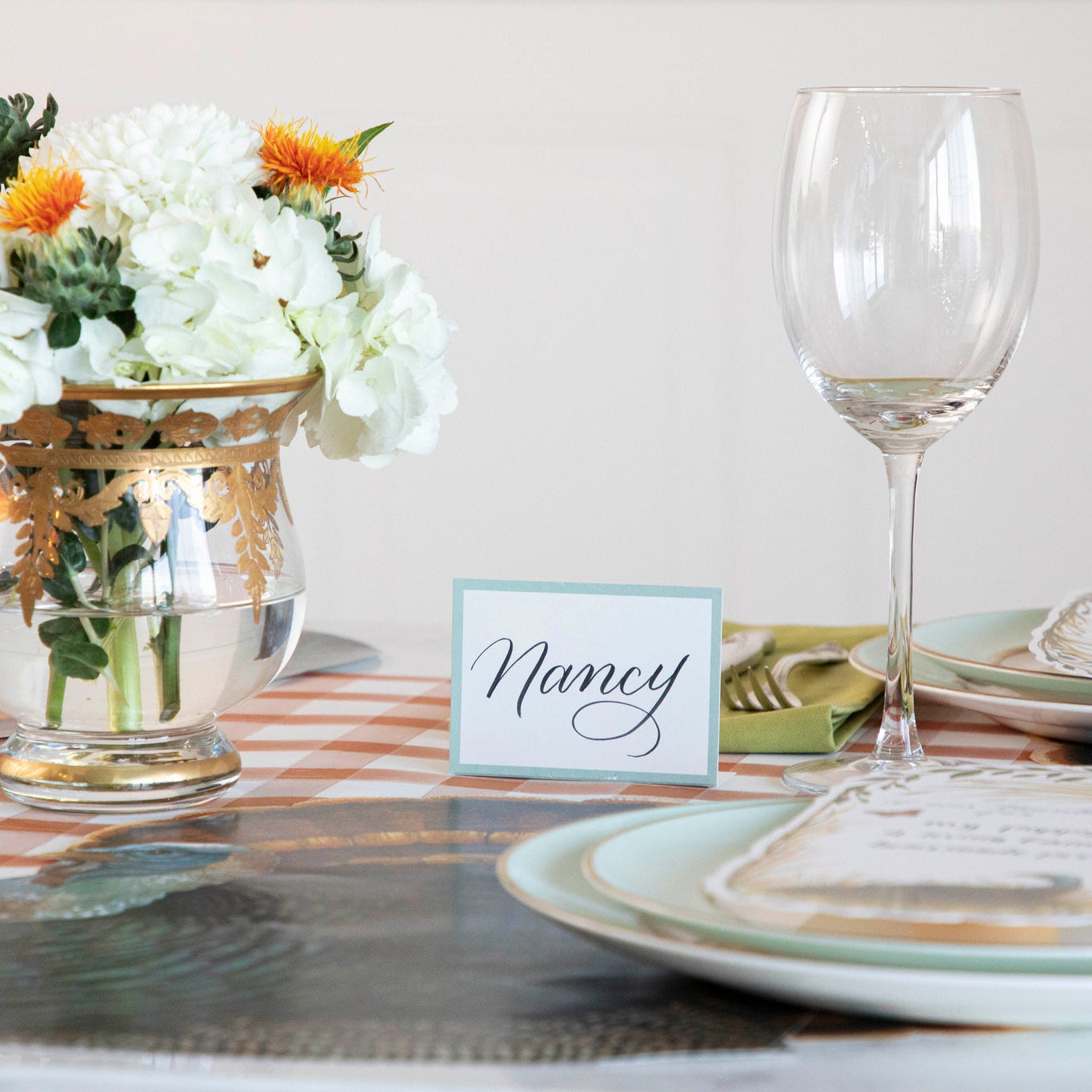 Seafoam Place Card reading "Nancy" behind a Thanksgiving place setting.