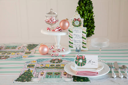 A festive Christmas table setting featuring a Clock Tower Table Card with a menu written on it in beautiful script standing up in a place card holder.