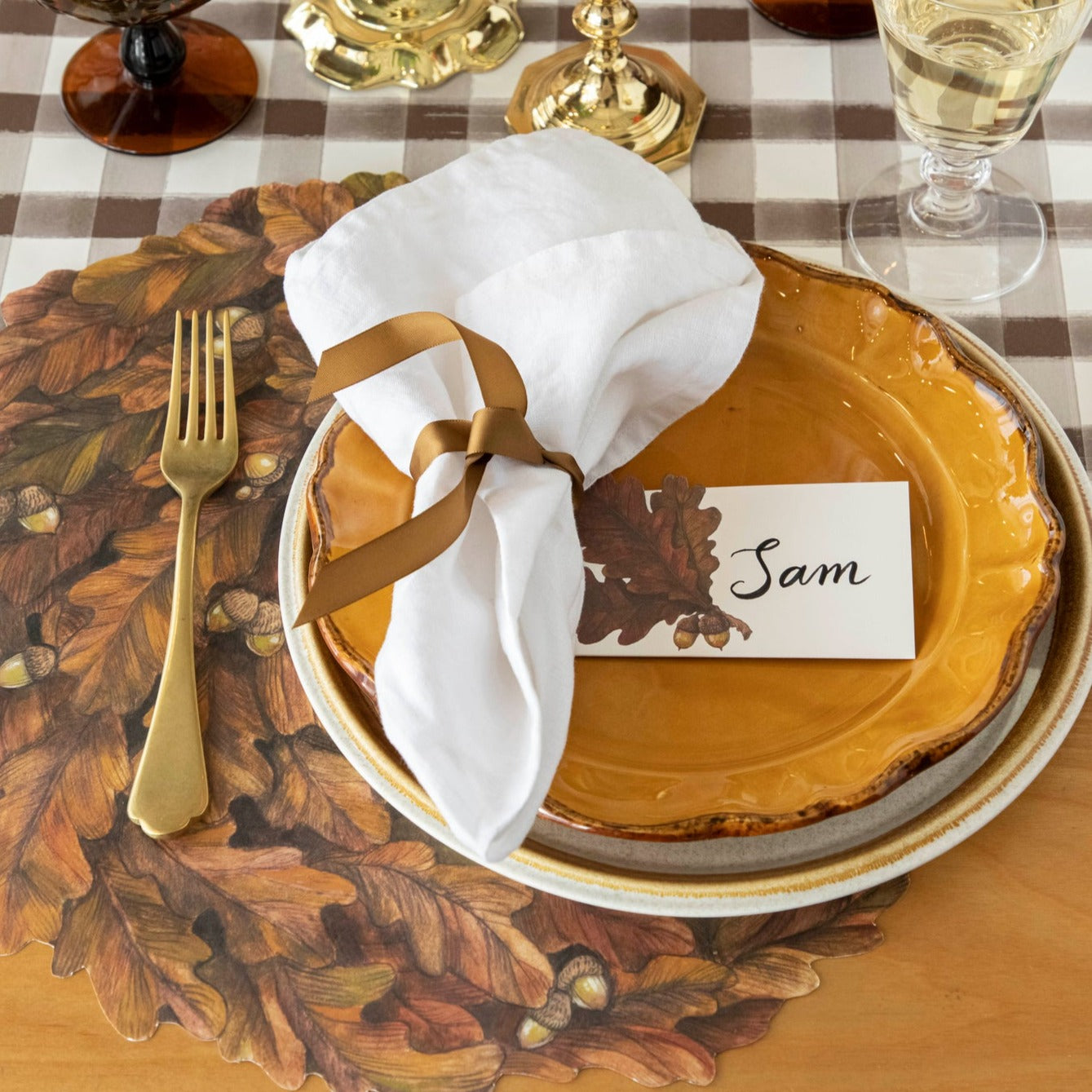 An elegant fall-themed place setting with a place card reading "Sam" laying flat on the plate.