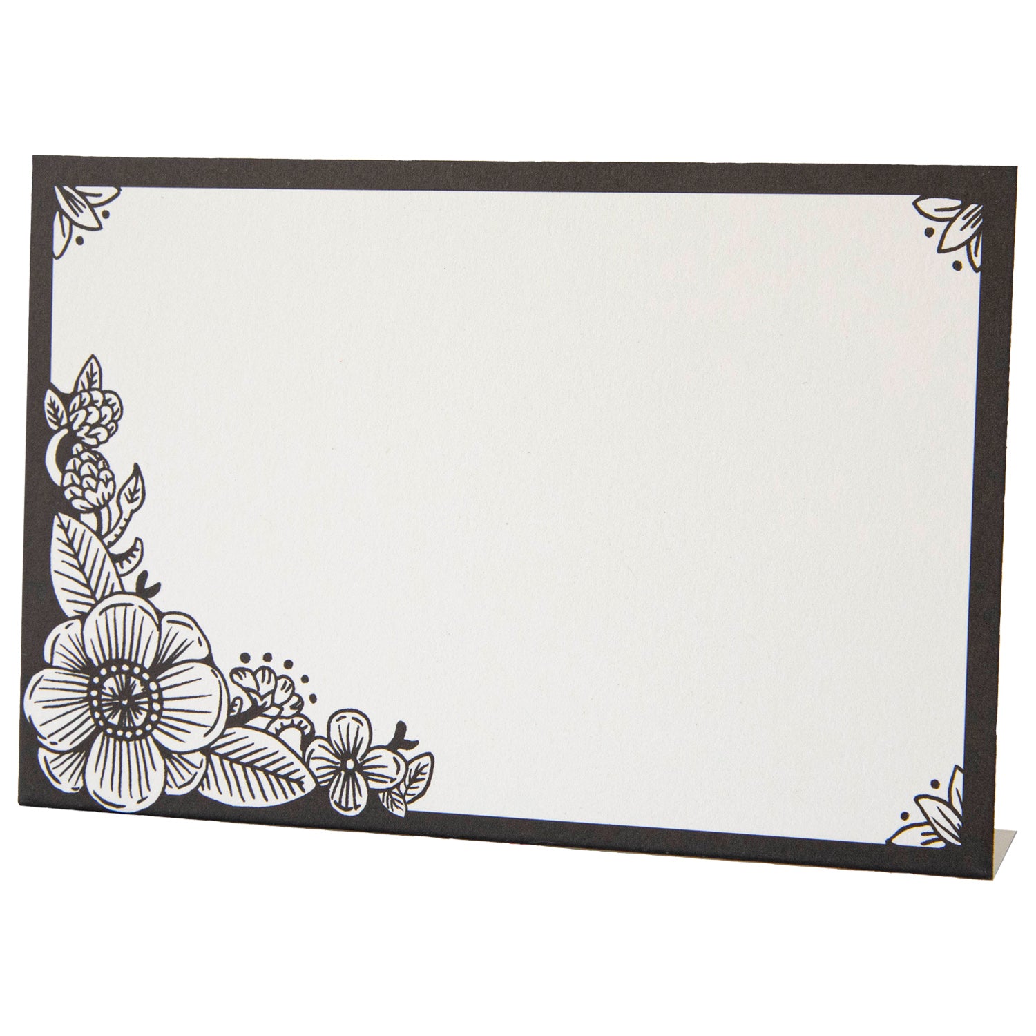 A free-standing, rectangular white table card with a black frame around the edges, embellished with black linework flower designs in the corners.