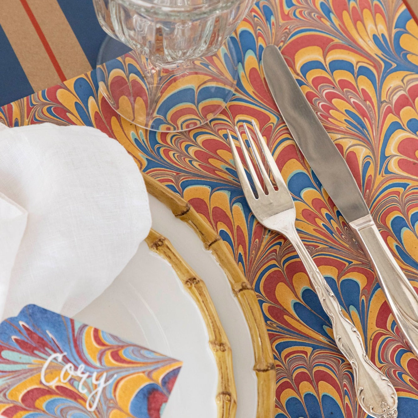 Close-up of the Red &amp; Blue Peacock Marbled Placemat under an elegant place setting.
