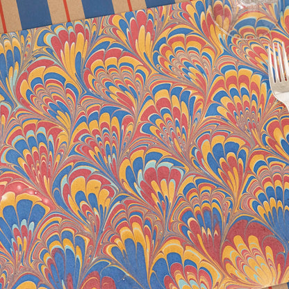 Close-up of the Red &amp; Blue Peacock Marbled Placemat on a place setting, showing the colorful swirls in detail.