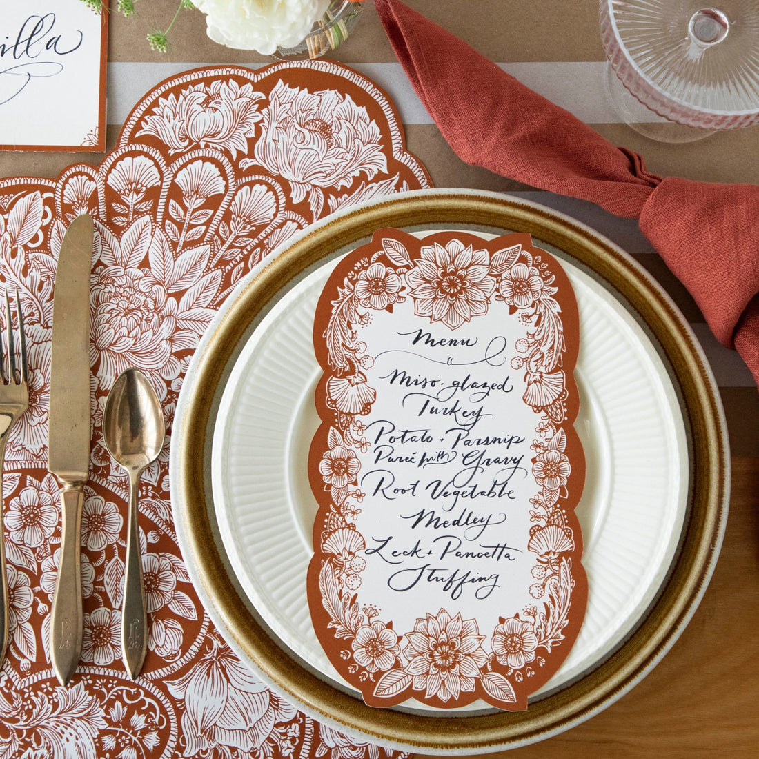 An elegant Fall place setting featuring a Harvest Blooms Table Card with a menu written on it resting on the plate.