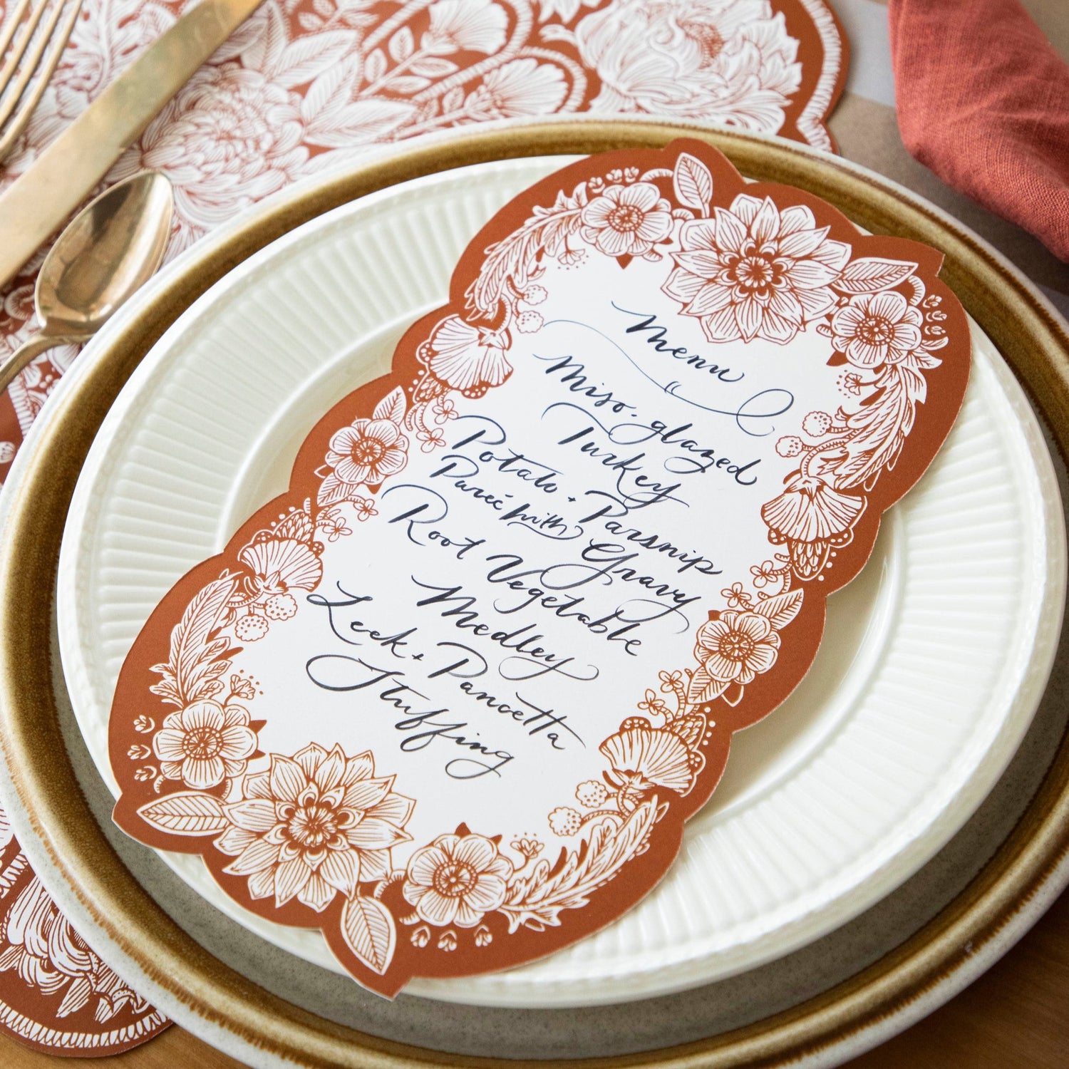 Close-up of an elegant Fall place setting featuring a Harvest Blooms Table Card with a menu written on it resting on the plate.