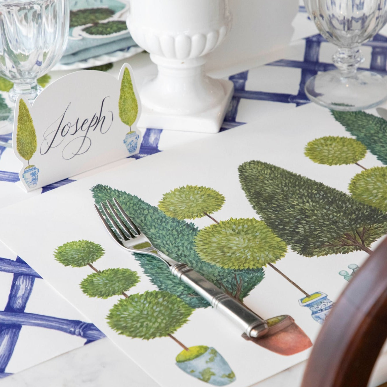 Close-up of the Topiary Garden Placemat in a place setting, showing the illustrated foliage in detail.
