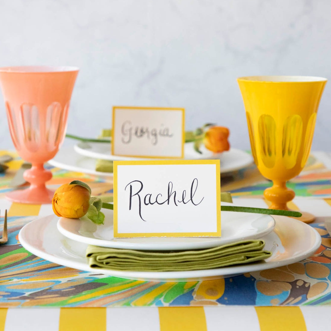 A table setting with Hester &amp; Cook Marigold Frame Place Card on a colorful tablecloth for year round celebrations.