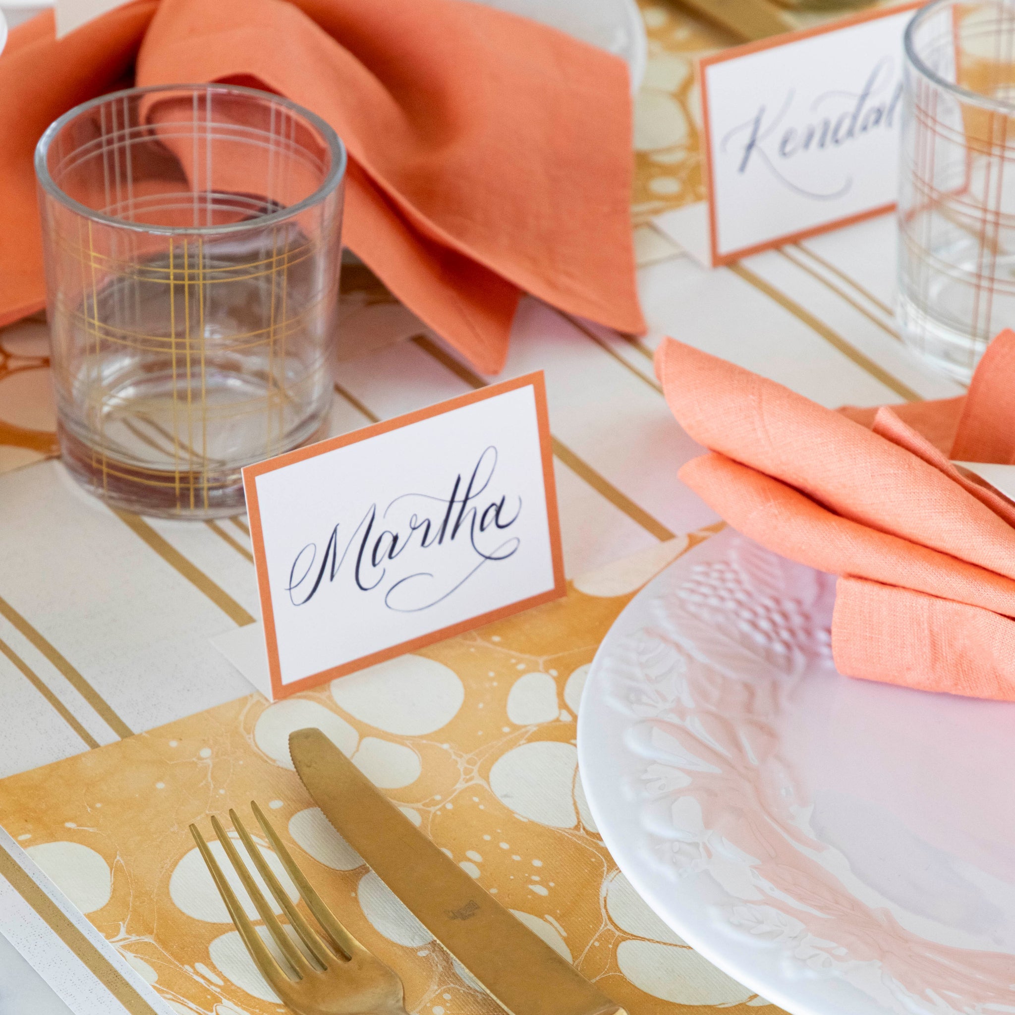 Orange Frame Place Card with "Martha" written in the white space, behind an elegant place setting.