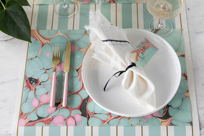 The Seafoam &amp; Red Stone Marbled Placemat under an elegant place setting.