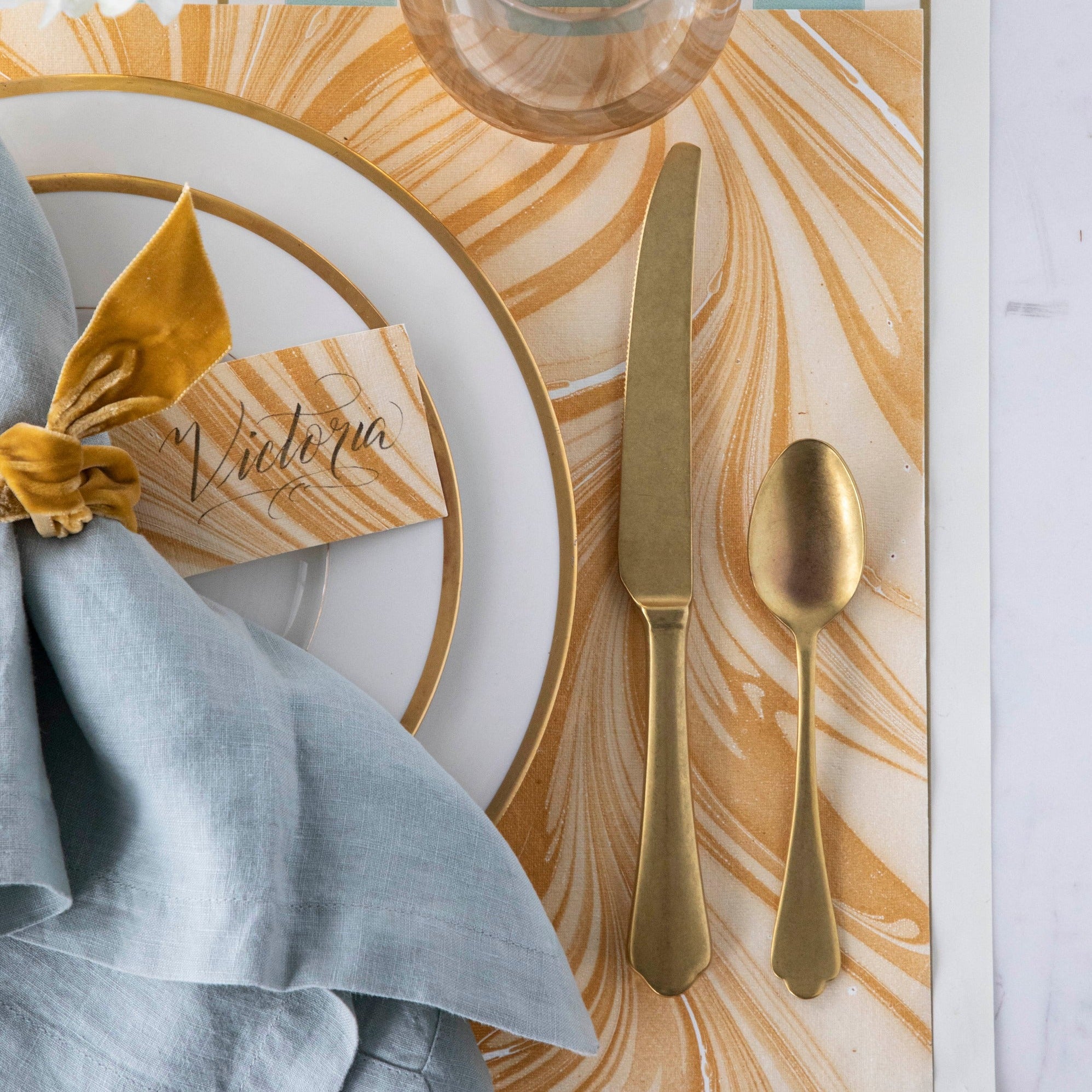 Close-up of the Gold Leaf Marbled Placemat under an elegant place setting, from above.