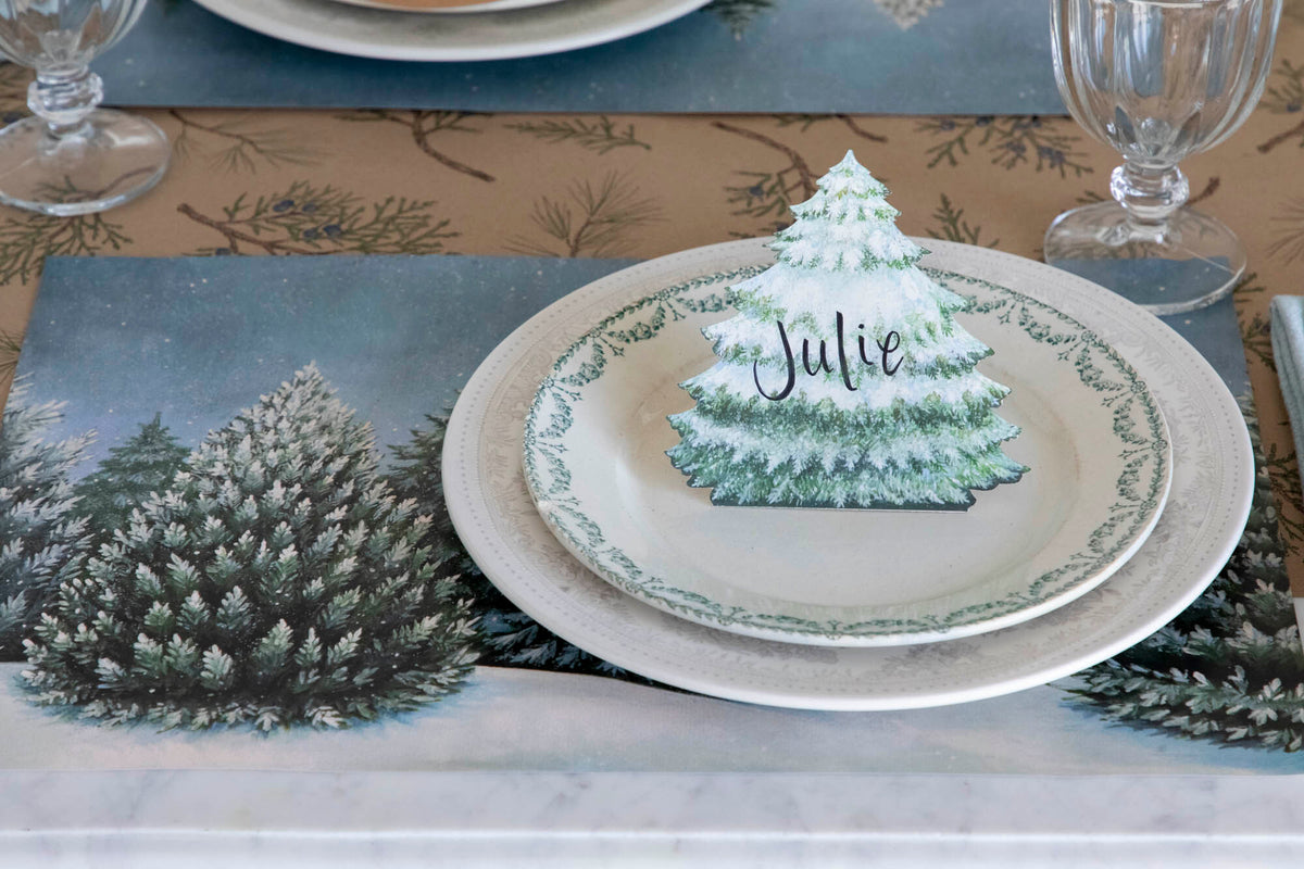 An elegant winter place setting featuring an Evergreen Place Card labeled "Julie" standing on the plate.