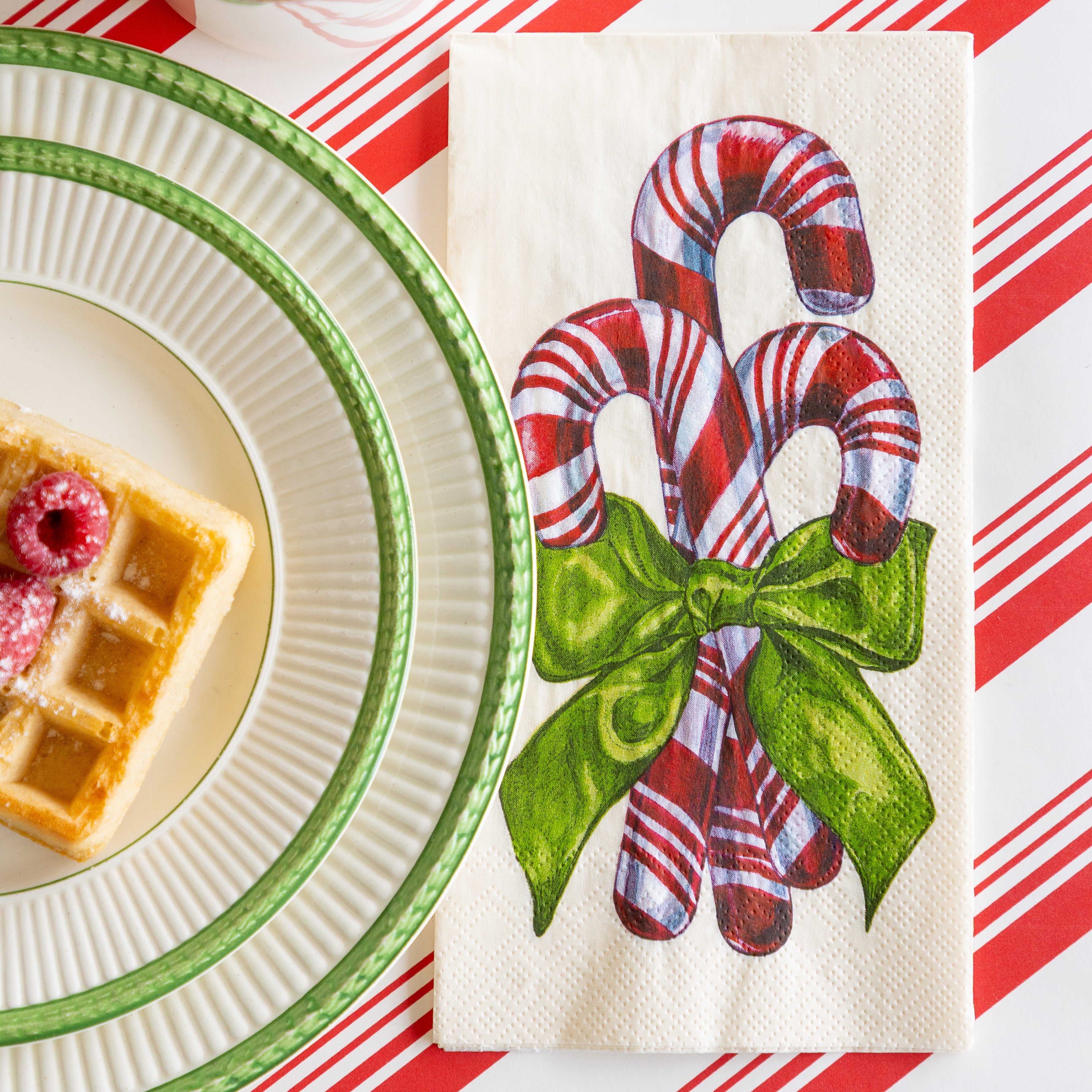 The Candy Cane Guest Napkin next to a plate of waffles, on the Peppermint Stripe Runner.