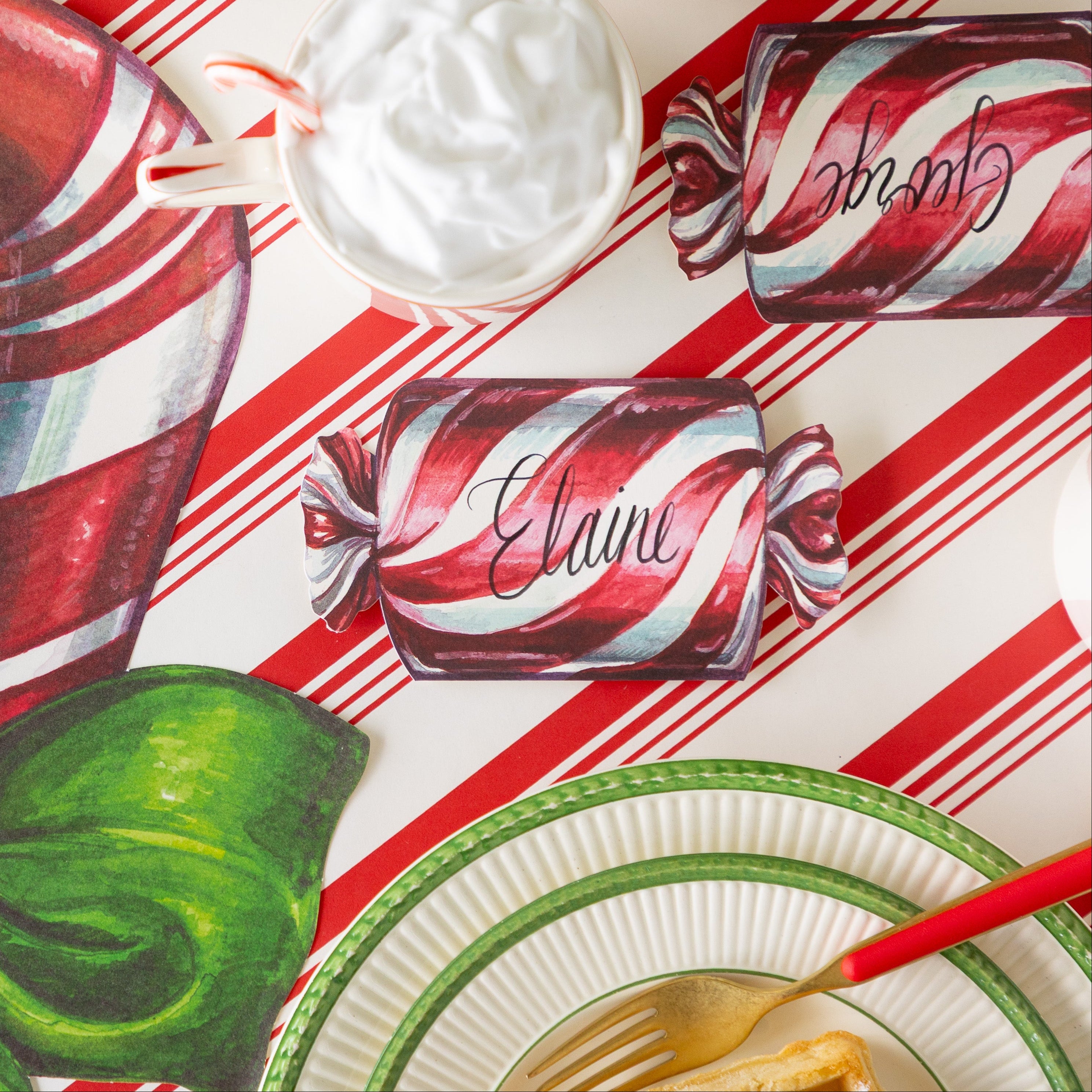 The Christmas Candy Place Card reading "Elaine" behind a place setting, on the Peppermint Stripe runner.