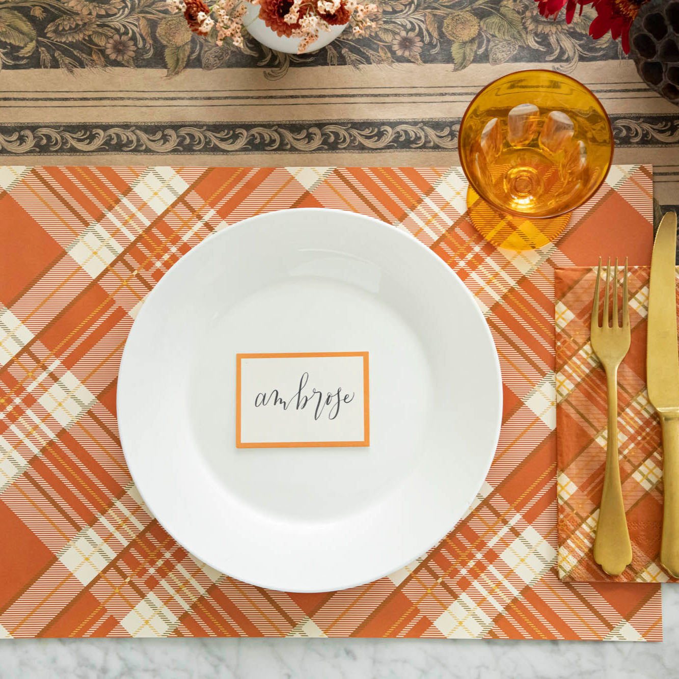 Orange Frame Place Card with "Ambrose" written in script, on the plate of a place setting.