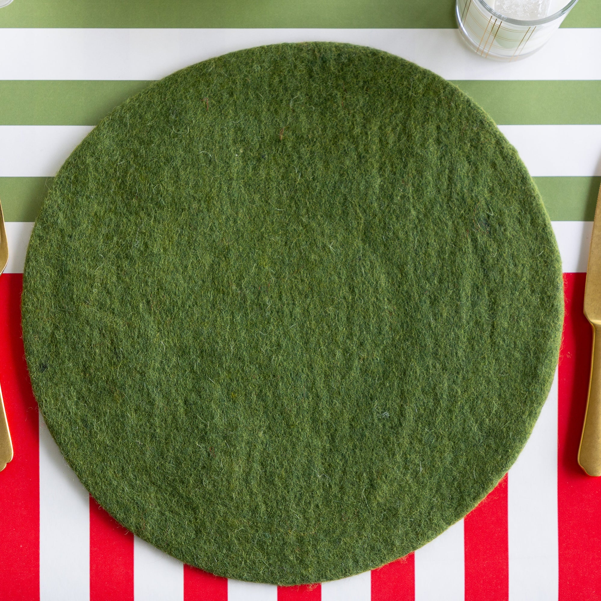 A place setting featuring the Forest Green Felt Placemat and gold flatware on the Red Classic and Moss Classic Stripe Runners.