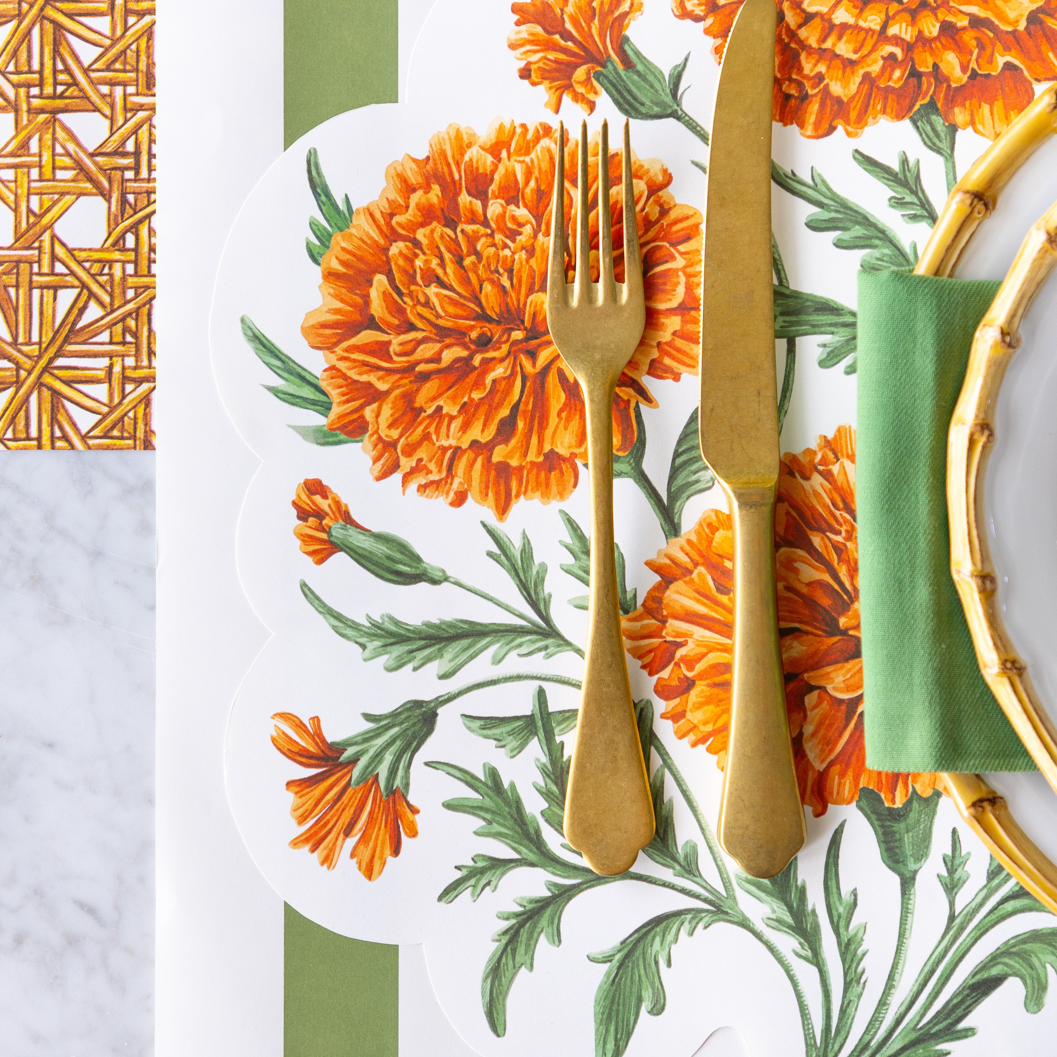 The Die-cut Marigold Bouquet Placemat under an elegant place setting with a gold fork and knife, Moss Classic Stripe Runner vertically under the place setting and Rattan Weave Runner horizontally under that.
