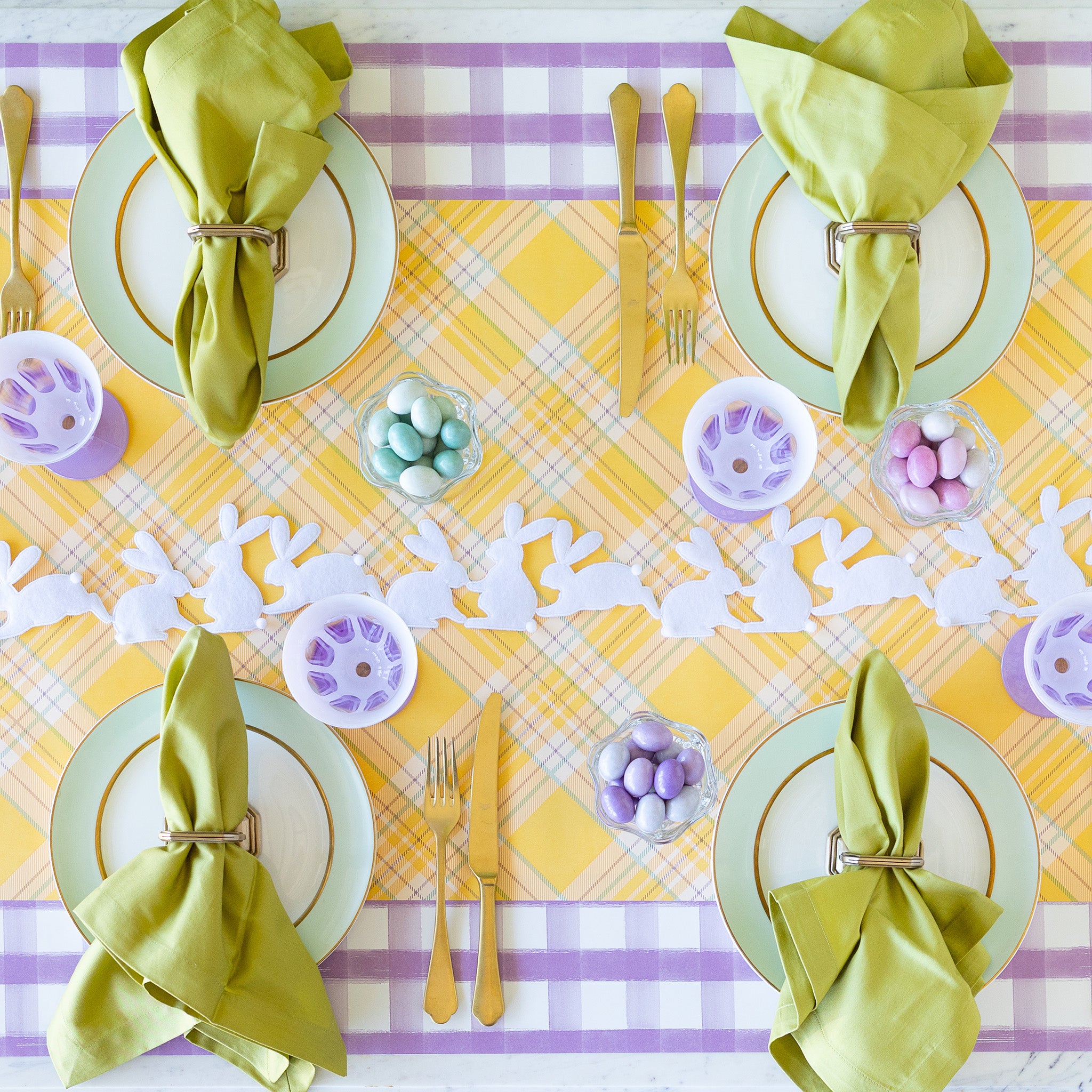 Rabbit Garland Ribbon with white appliqué rabbits made of felt running down a table with a yellow plaid runner and purple glasses on it.