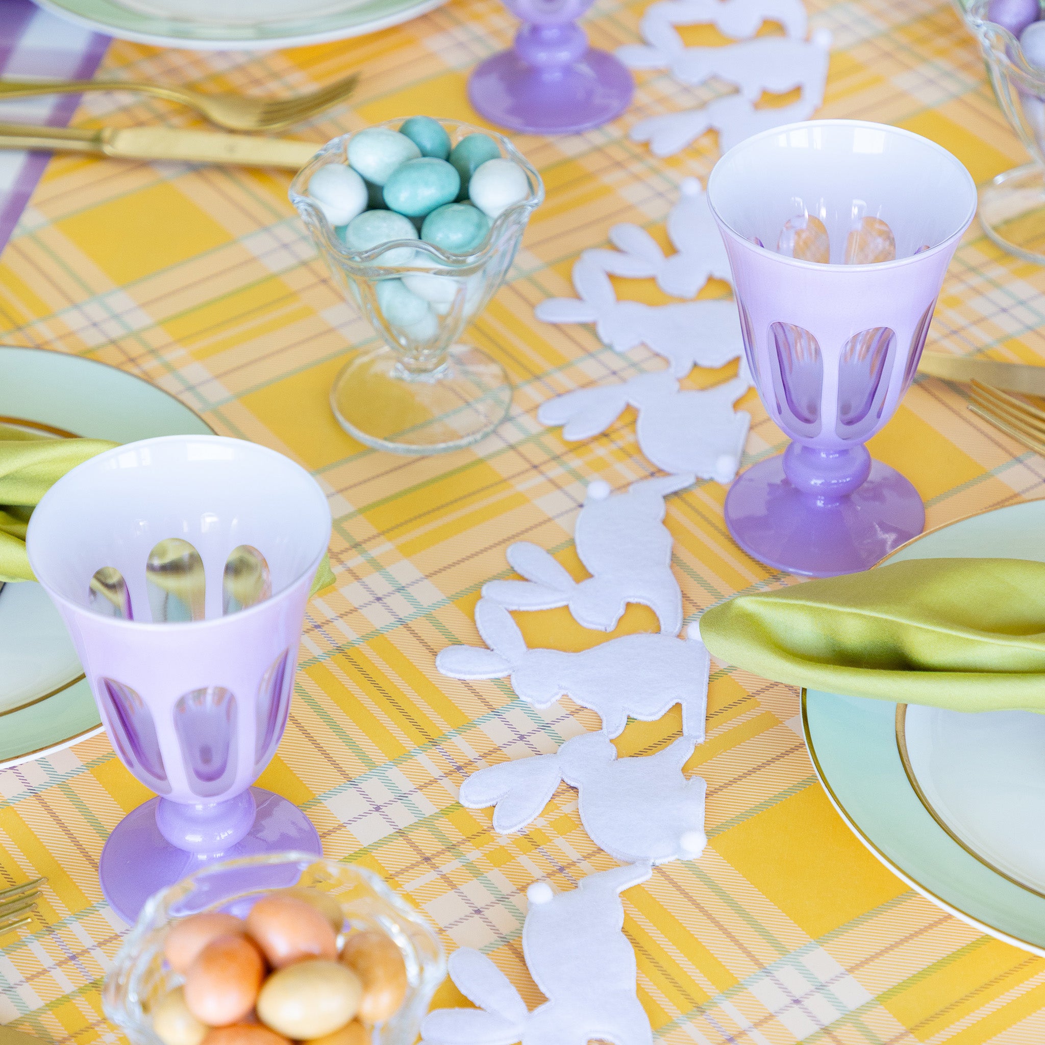 Rabbit Garland Ribbon with white appliqué rabbits made of felt running down a table with a yellow plaid runner and purple glasses on it.