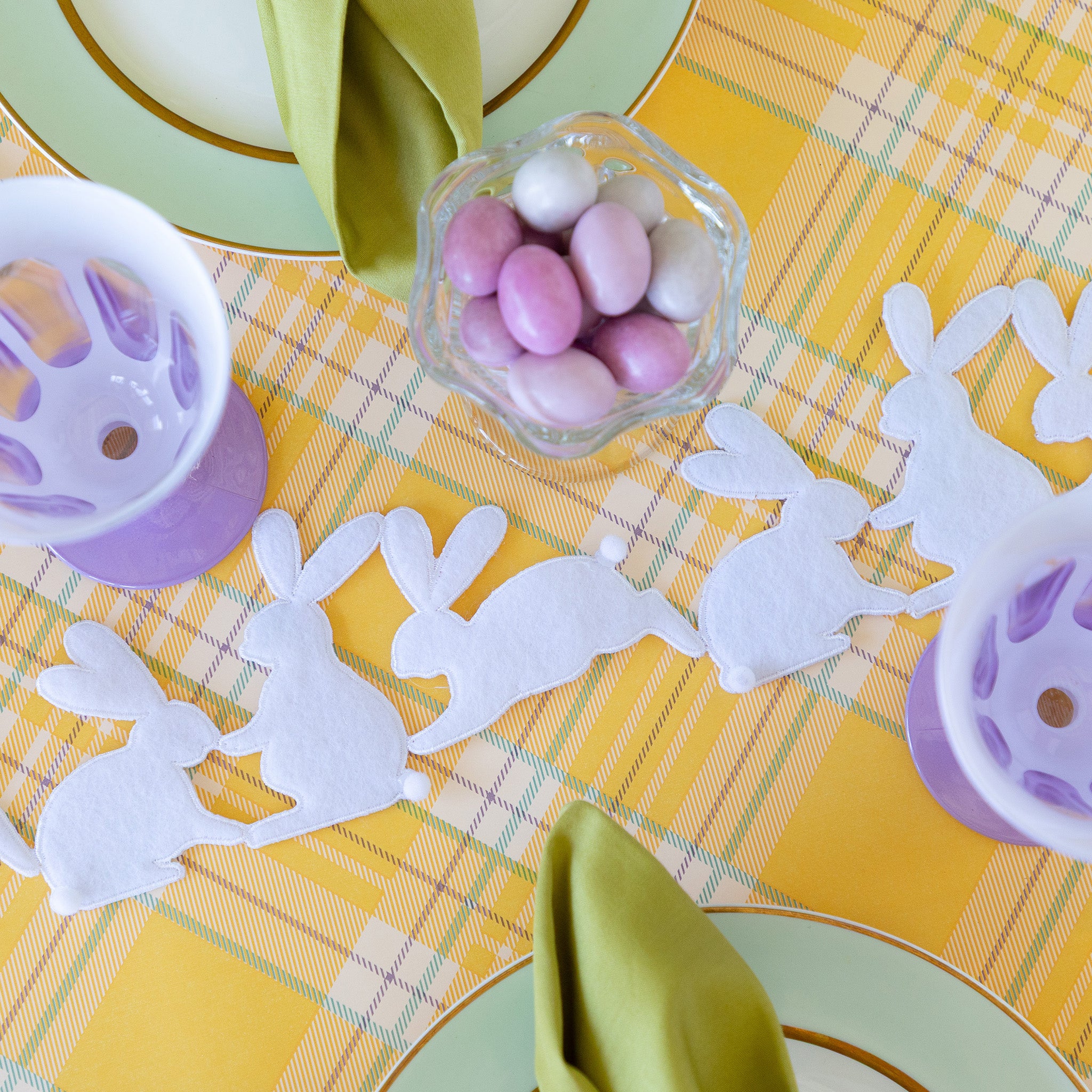 Rabbit Garland Ribbon with white appliqué rabbits made of felt running down a table with a yellow plaid runner and purple glasses on it.