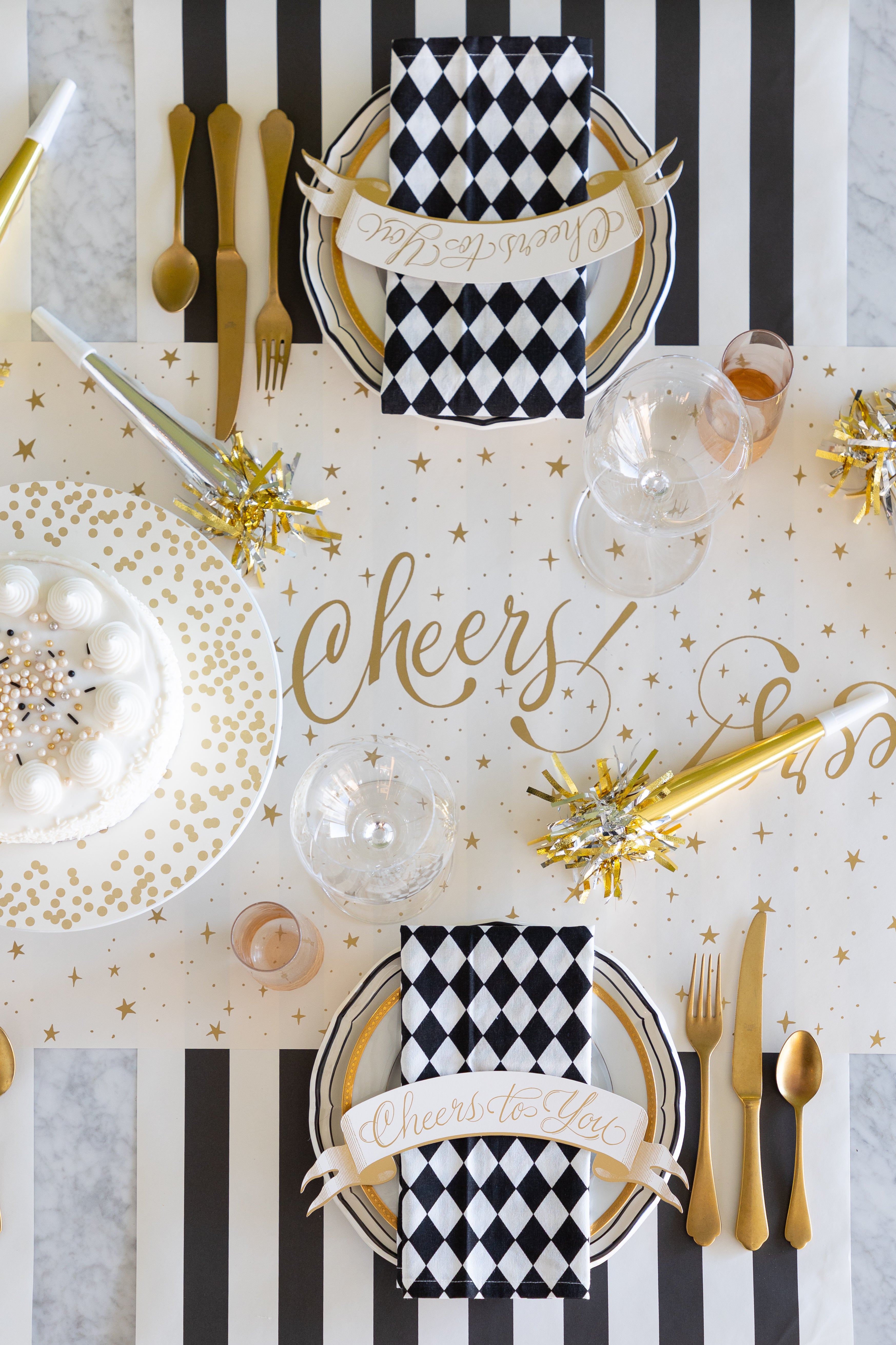Decorative table setting with black and white checkered napkins, gold cutlery, and &