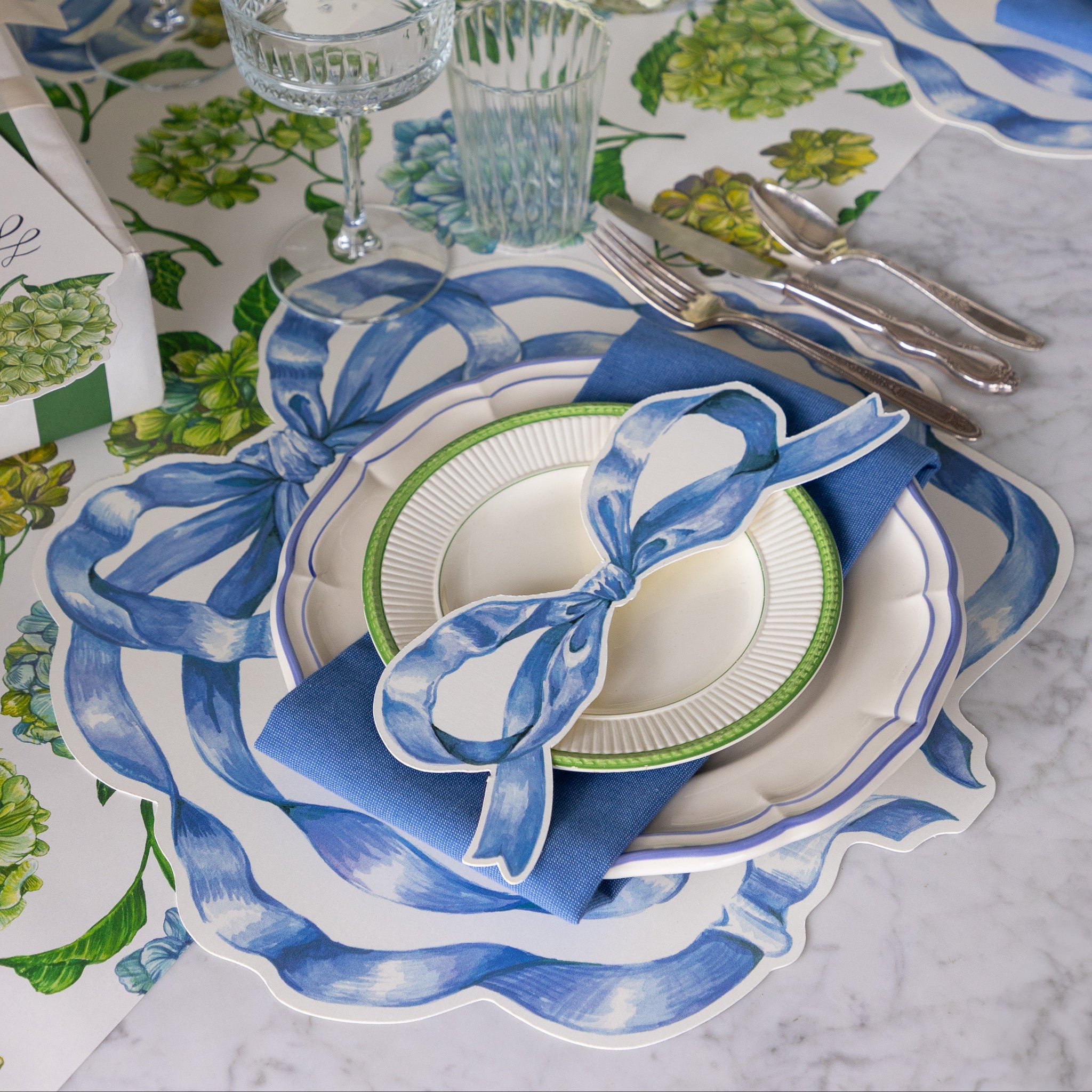 Elegant table setting with the Die-cut Heirloom Blue Bow Placemat, Heirloom Blue Bow Table Accent and blue napkin on the Hydrangea Runner.