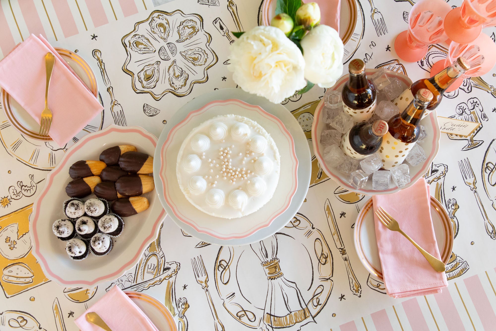 Decorative table setting with plates, napkins, and drinks on a patterned tablecloth.