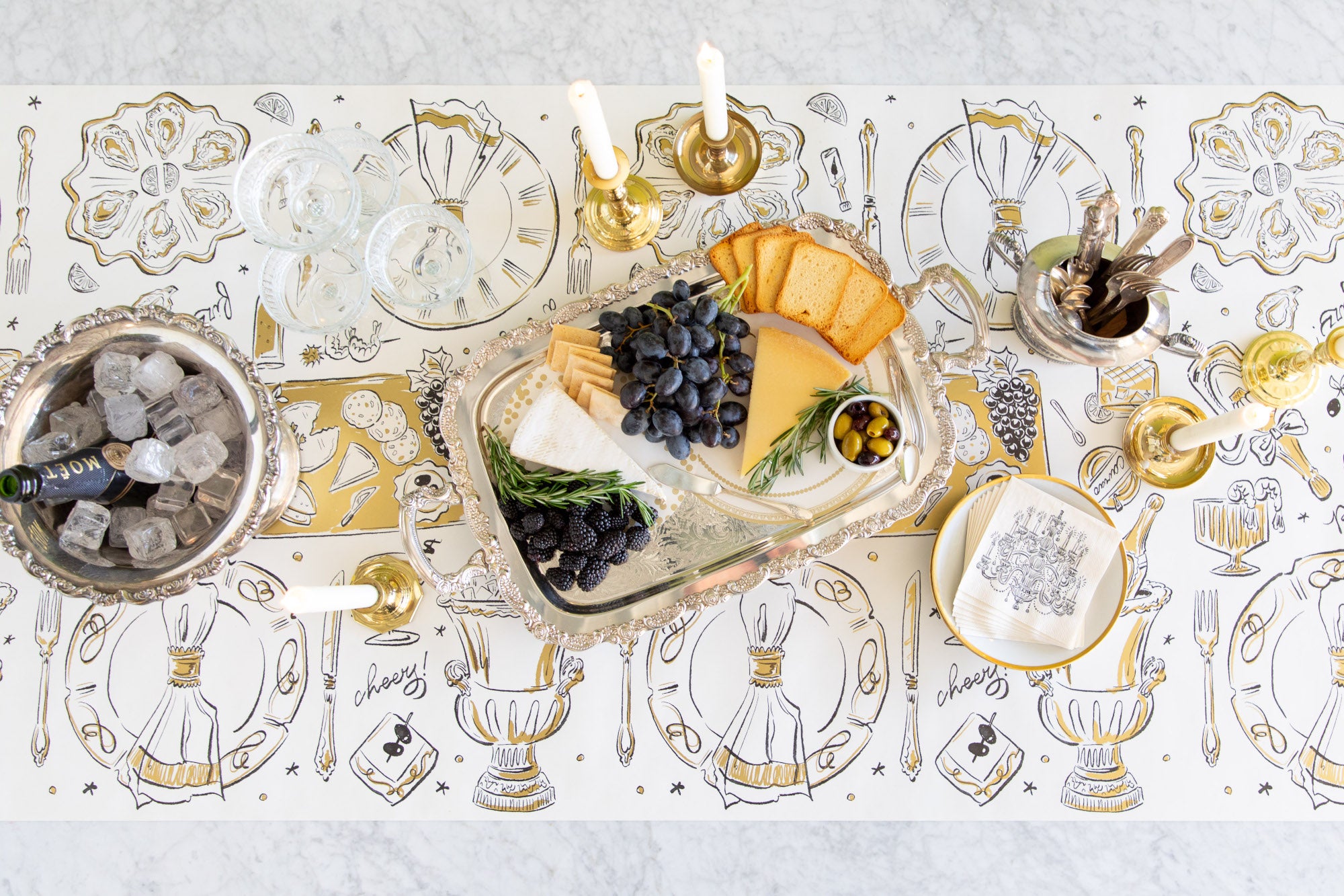 Table Runner with hand drawn illustrations of party tabletop items with a bucket of champagne, candle holders and a charcuterie tray set upon it.