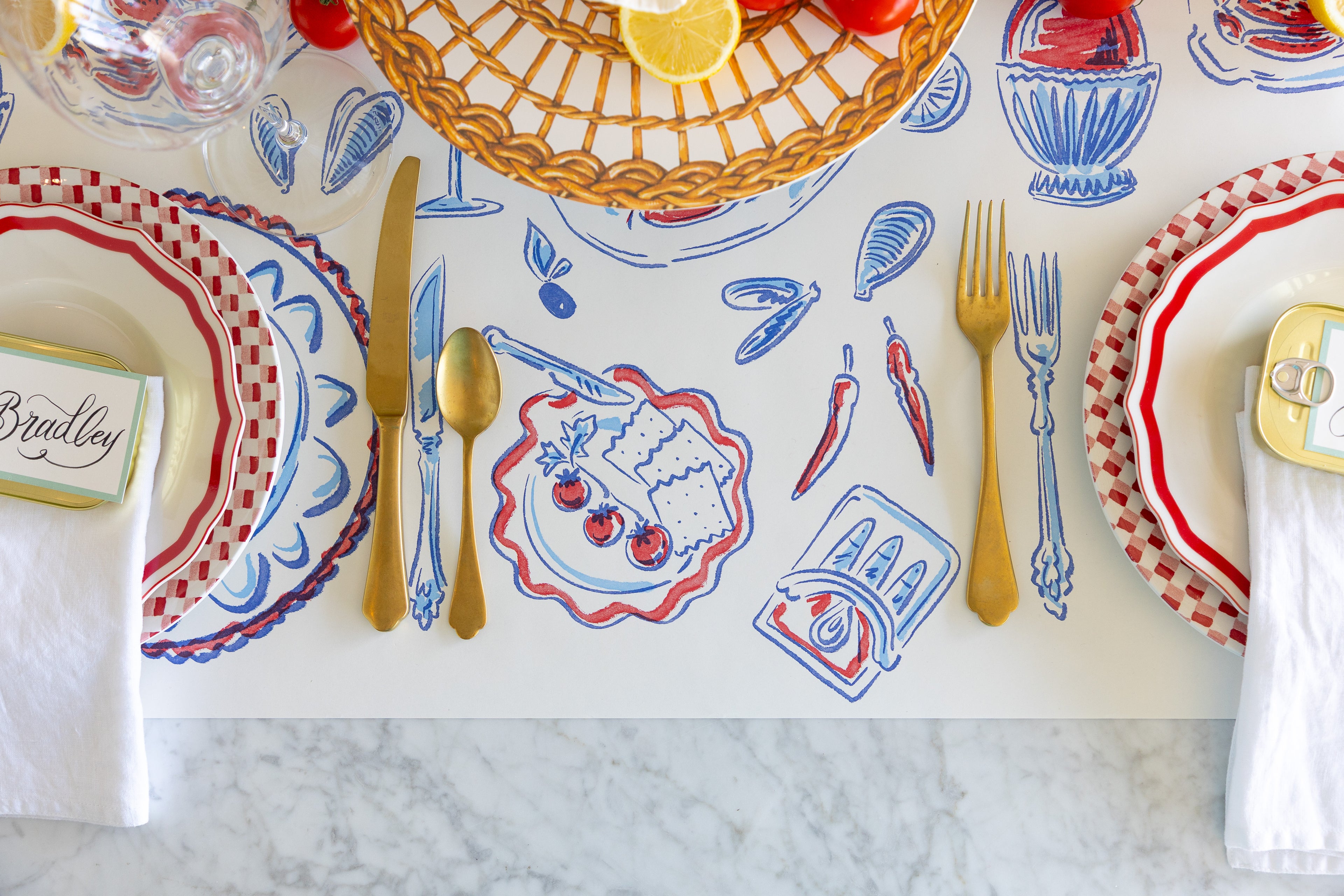 Dining table setting with decorative placemat, plates, and cutlery on a marble surface.