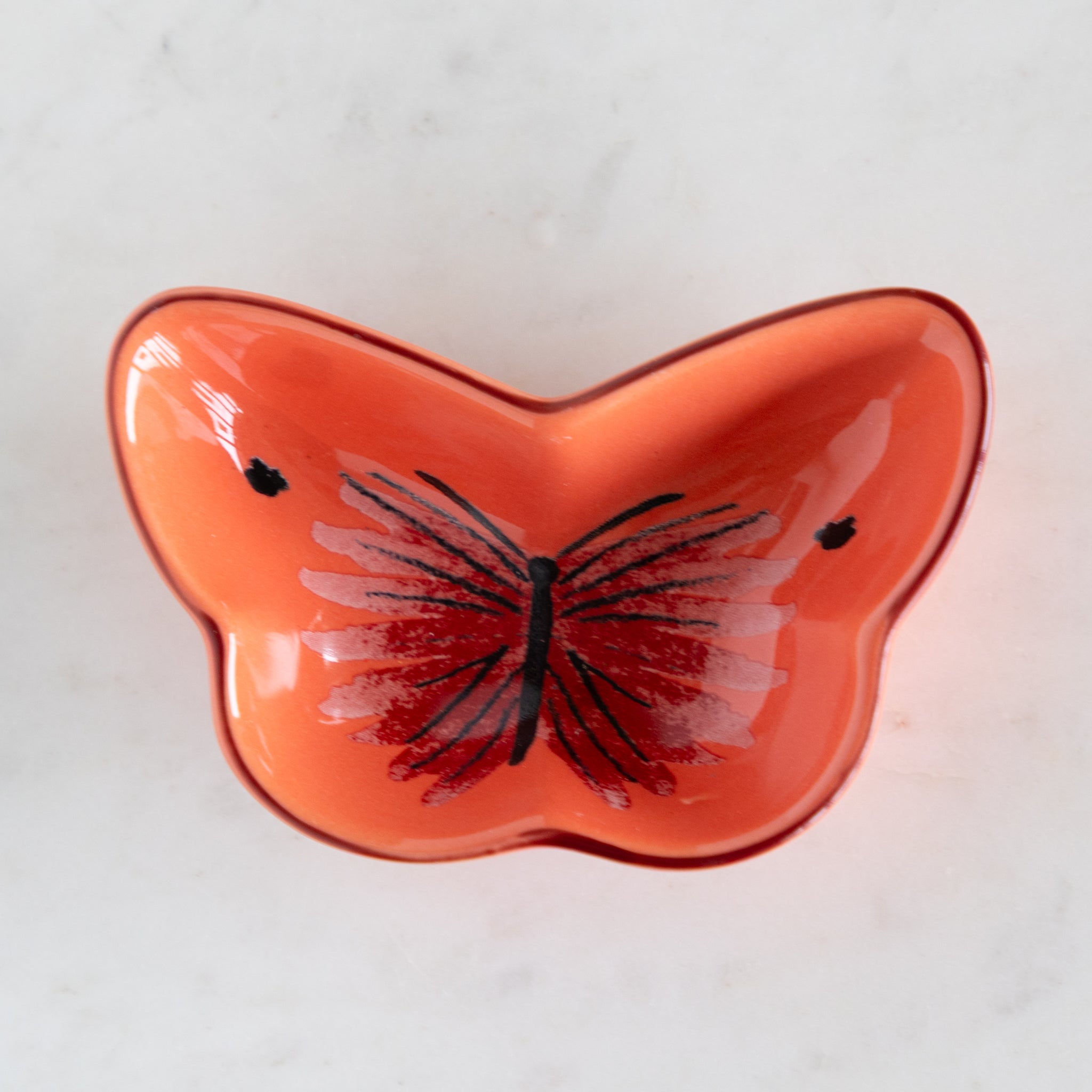 Butterfly-shaped orange dish on a white background.