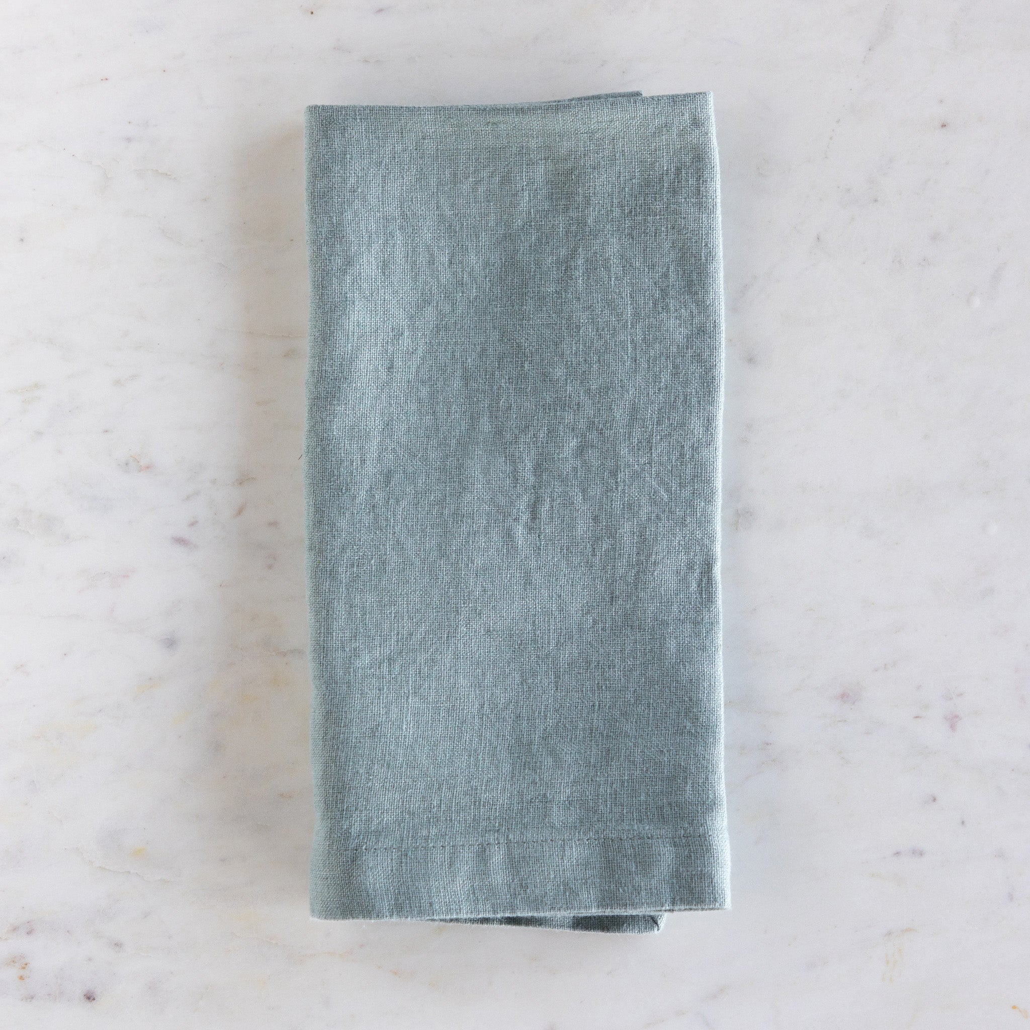 Folded green napkin on a marble surface.