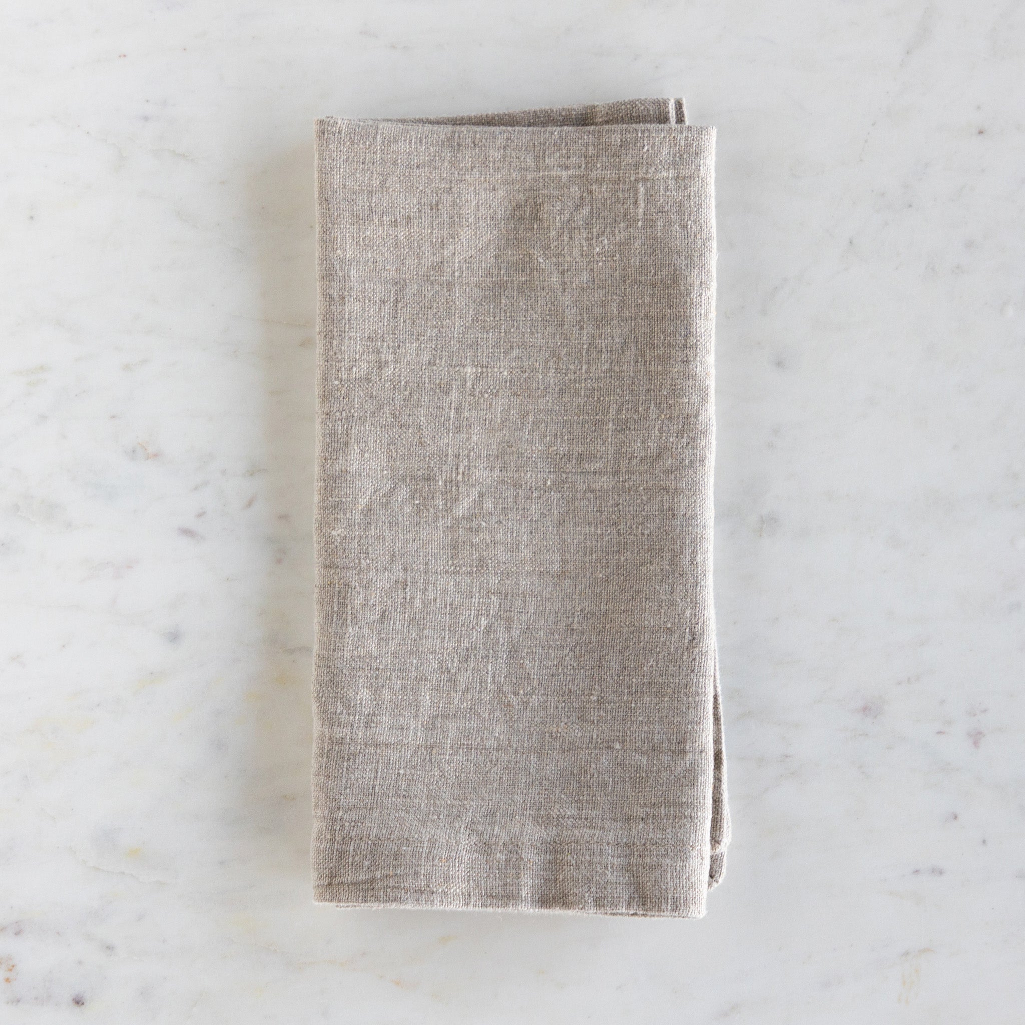 Folded beige napkin on a marble surface.