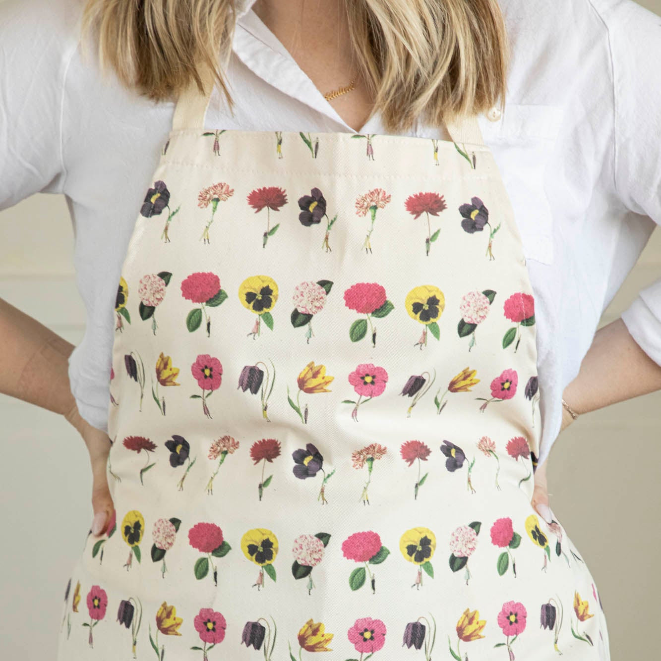 A woman wearing the In Bloom Apron by Laura Stoddart.