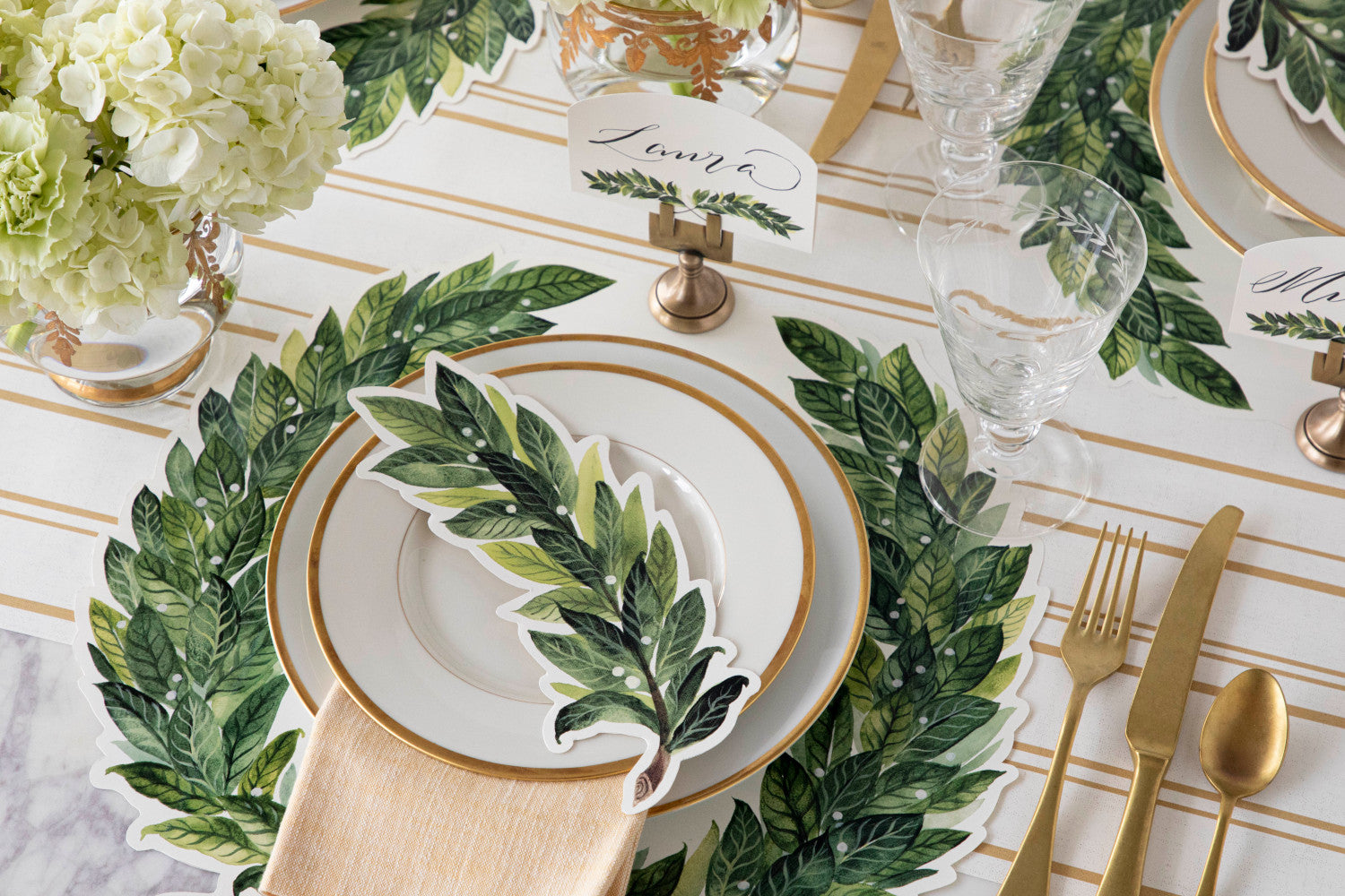 An elegant place setting with gold accents featuring a Laurel Table Accent resting on the plate.