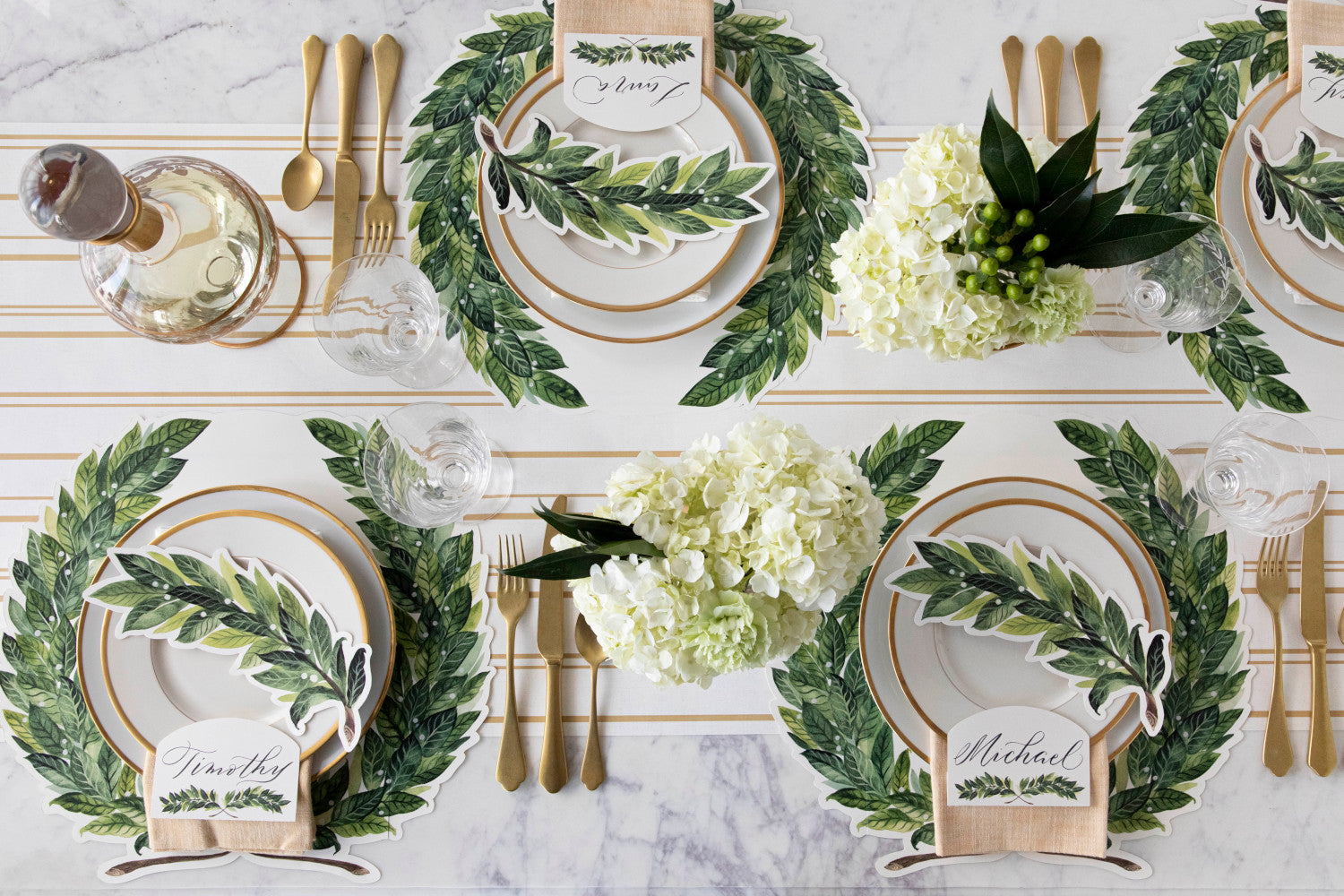 The Die-cut Green Laurel Wreath Placemat under an elegant table setting for four, from above.