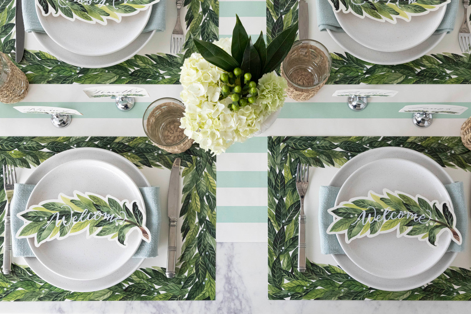 An elegant table setting for four featuring Laurel Table Accents resting on each plate.