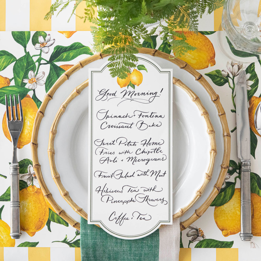 Top-down view of a bright citrus-themed place setting featuring a Lemon Table Card with a menu written on it resting on the plate.