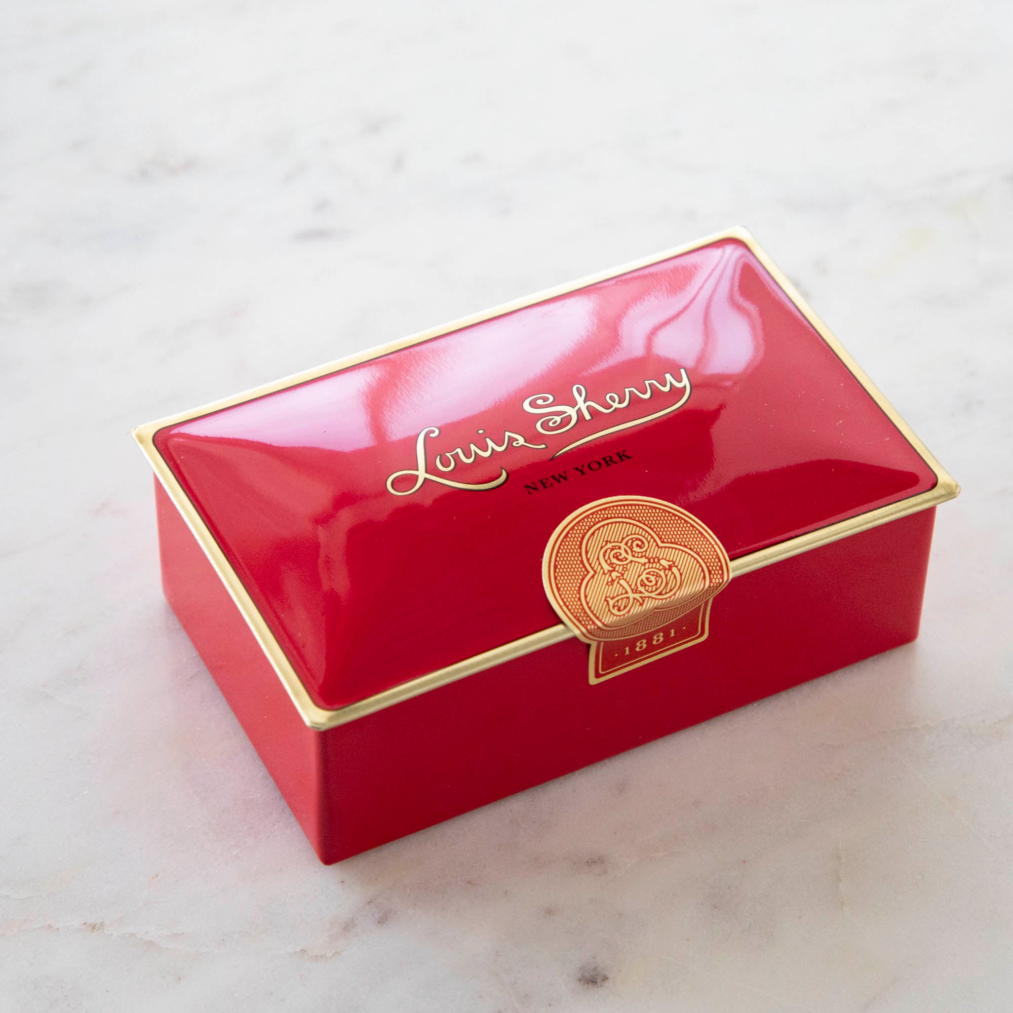 Tin Louis Sherry chocolate box in bright red with gold details.