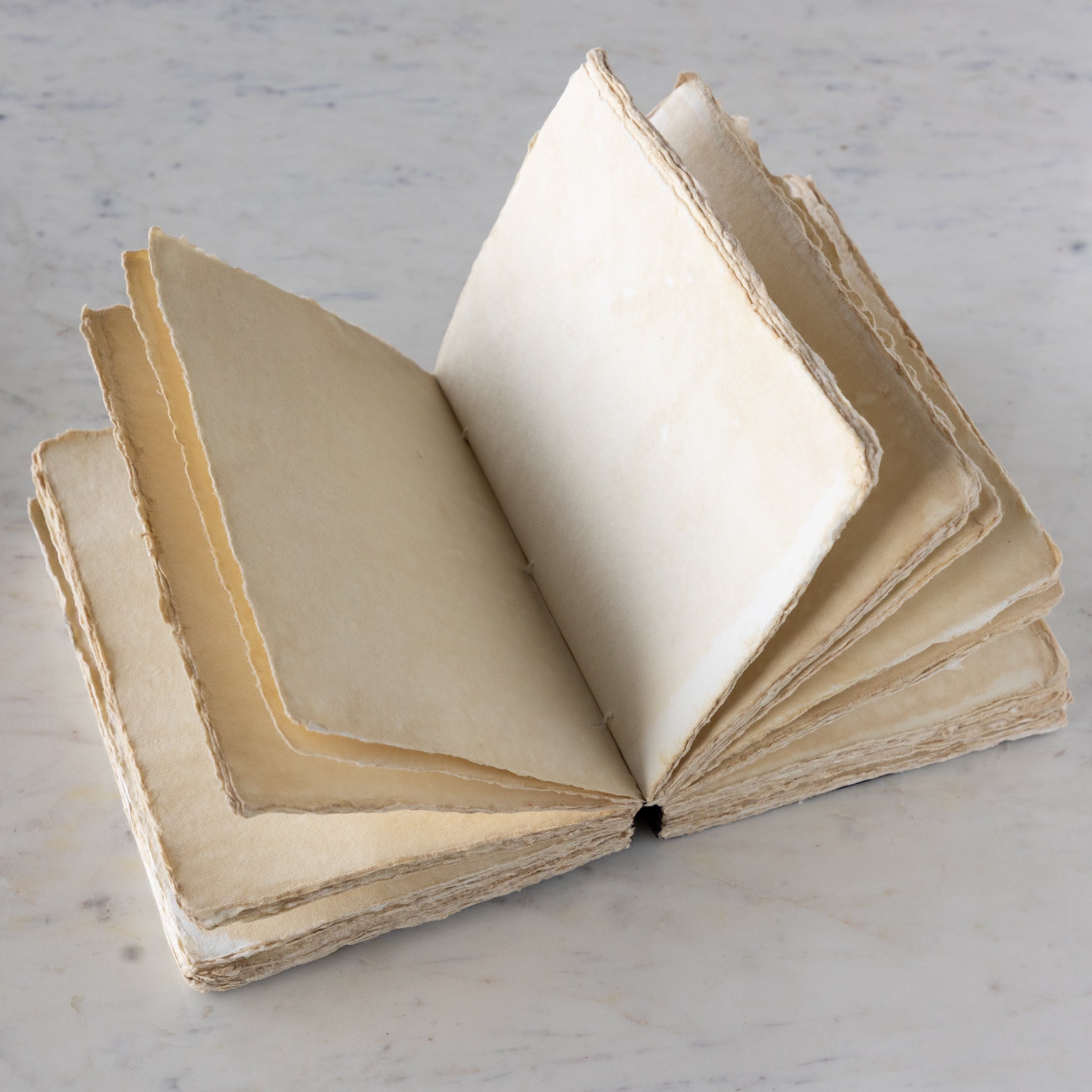 Open vintage notebook on a marble surface.